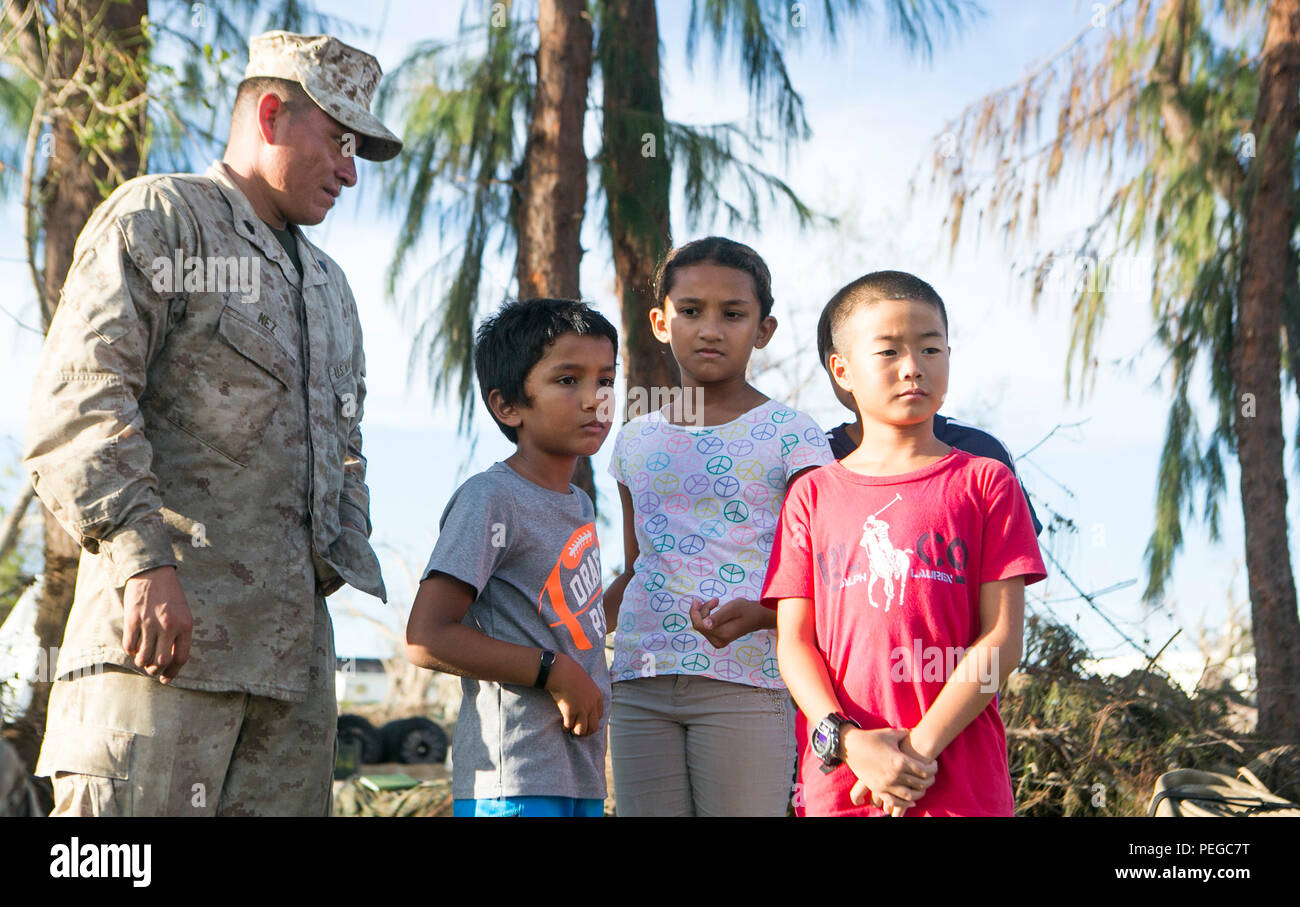 U.S. Marine Sgt. Theron Nez, with Combat Logistics Battalion 31, 31st Marine Expeditionary Unit, shows local children a Light Weight Purification System at a water purification site in Saipan, Aug. 10, 2015. The 31st MEU and the ships of the Bonhomme Richard Amphibious Ready Group are assisting federal and local agencies with distributing emergency relief supplies to Saipan after it was struck by Typhoon Soudelor, Aug. 2-3. (U.S. Marine Corps photo by Lance Cpl. Brian Bekkala/Released) Stock Photo