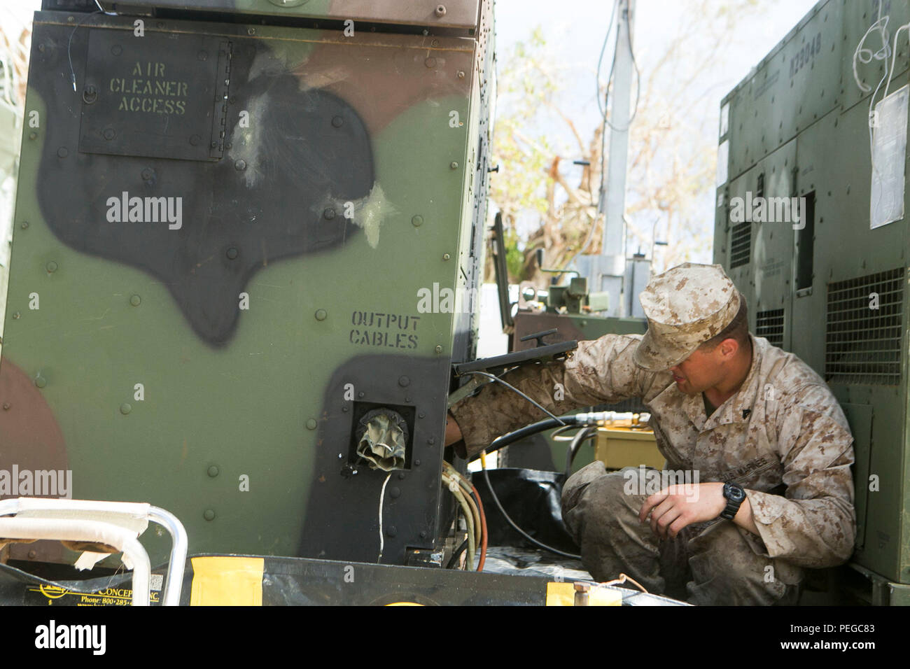 U.S. Marine Corps Cpl. Colton Santic, with Combat Logistics Battalion 31, 31st Marine Expeditionary Unit, works on a MEP 806 Generator while Marines distribute water to local civilians as part of typhoon relief efforts in Saipan, Aug. 11, 2015. The 31st MEU and the ships of the Bonhomme Richard Amphibious Ready Group are assisting the Federal Emergency Management Agency with distributing emergency relief supplies to Saipan after the island was struck by Typhoon Soudelor, Aug. 2-3. (U.S. Marine Corps photo by Lance Cpl. Brian Bekkala/Released.) Stock Photo