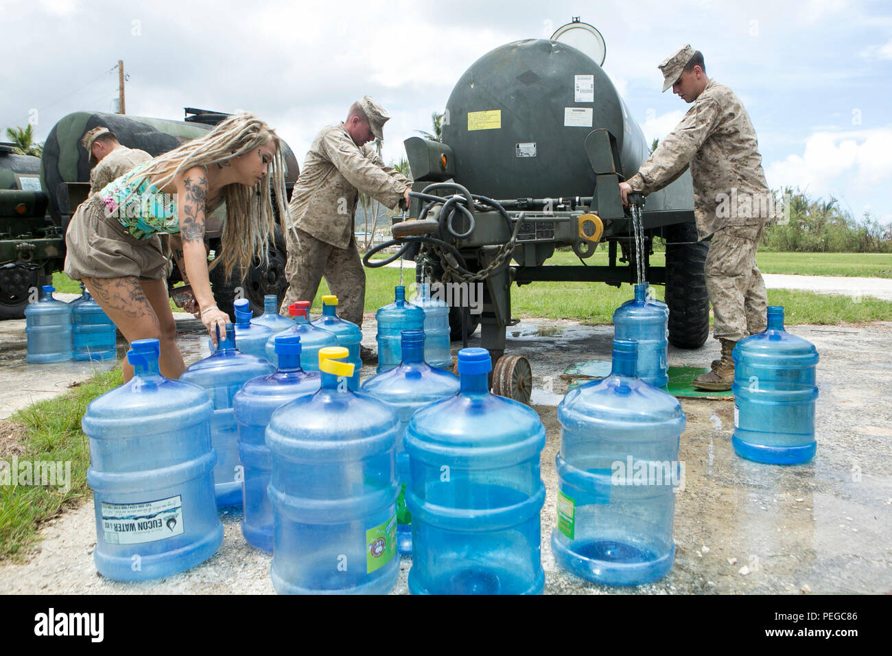 A young woman sets up her water jugs to be filled at a water distribution site set up by U.S. Marines from Combat Logistics Battalion 31, 31st Marine Expeditionary Unit, as part of typhoon relief efforts in Saipan, Aug. 11, 2015. The 31st MEU and the ships of the Bonhomme Richard Amphibious Ready Group are assisting the Federal Emergency Management Agency with distributing emergency relief supplies to Saipan after the island was struck by Typhoon Soudelor, Aug. 2-3. (U.S. Marine Corps photo by Lance Cpl. Brian Bekkala/Released.) Stock Photo