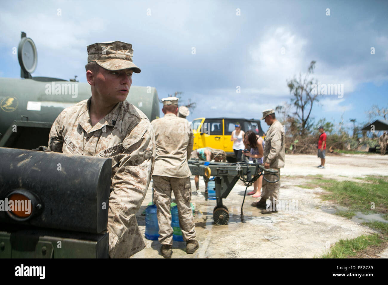U.S. Marine Cpl. Shamus King with Combat Logistics Battalion 31, 31st Marine Expeditionary Unit, distributes water to local civilians as part of typhoon relief efforts in Saipan, Aug. 11, 2015. The 31st MEU and the ships of the Bonhomme Richard Amphibious Ready Group are assisting the Federal Emergency Management Agency with distributing emergency relief supplies to Saipan after the island was struck by Typhoon Soudelor, Aug. 2-3. (U.S. Marine Corps photo by Lance Cpl. Brian Bekkala/Released.) Stock Photo