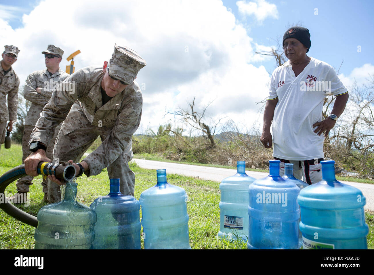 U.S. Marine 1st Lt. William Tidd, with Combat Logistics Battalion 31, 31st Marine Expeditionary Unit, distributes water to local civilians as part of typhoon relief efforts in Saipan, Aug. 11, 2015. The 31st MEU and the ships of the Bonhomme Richard Amphibious Ready Group are assisting the Federal Emergency Management Agency with distributing emergency relief supplies to Saipan after the island was struck by Typhoon Soudelor, Aug. 2-3. (U.S. Marine Corps photo by Lance Cpl. Brian Bekkala/Released.) Stock Photo