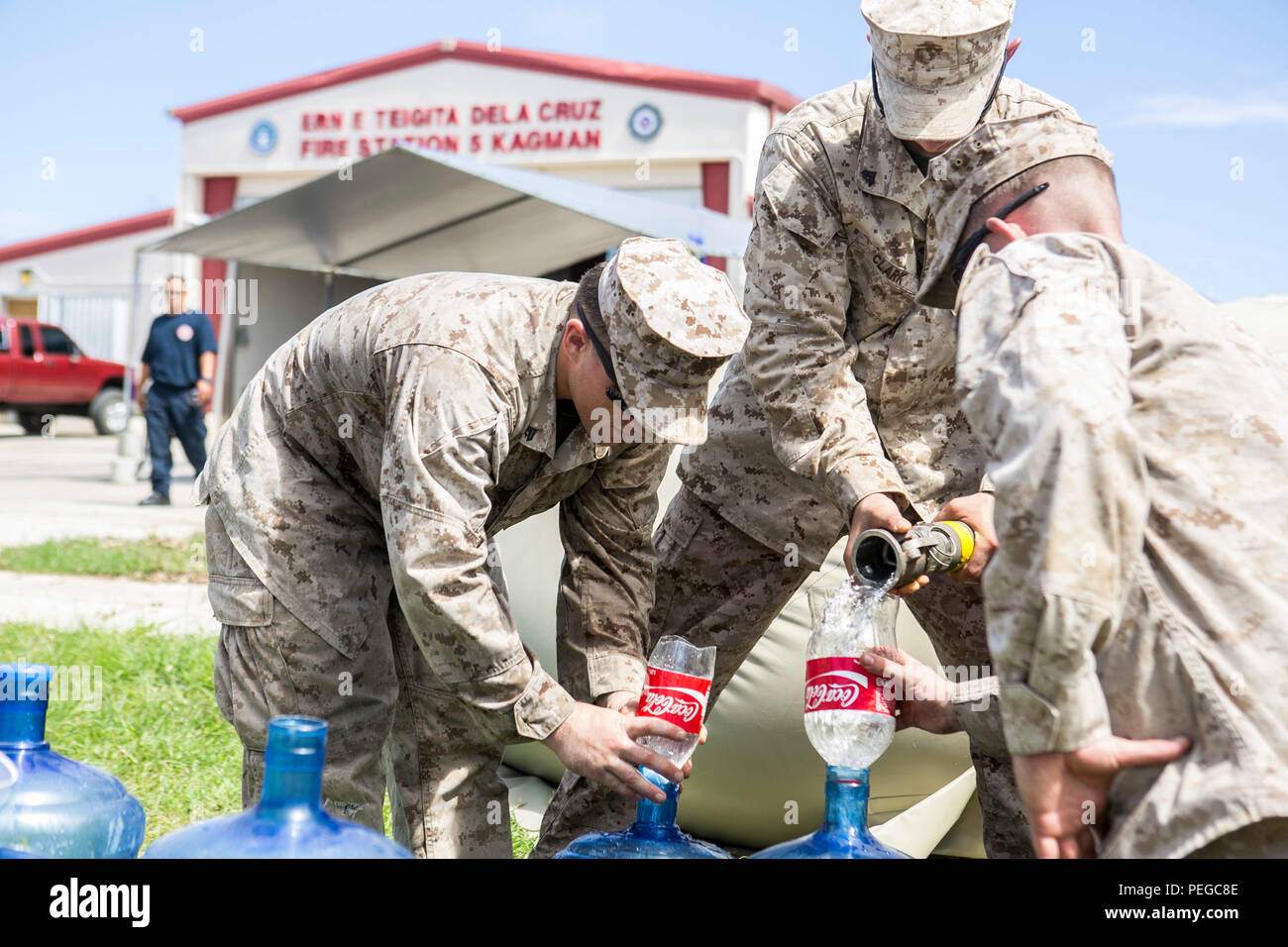 U.S. Marines with Combat Logistics Battalion 31, 31st Marine Expeditionary Unit, distribute water to  local civilians during typhoon relief efforts in Saipan, Aug. 11, 2015. The 31st MEU and the ships of the Bonhomme Richard Amphibious Ready Group are assisting the Federal Emergency Management Agency with distributing emergency relief supplies to Saipan after the island was struck by Typhoon Soudelor, Aug. 2-3. (U.S. Marine Corps photo by Lance Cpl. Brian Bekkala/Released.) Stock Photo