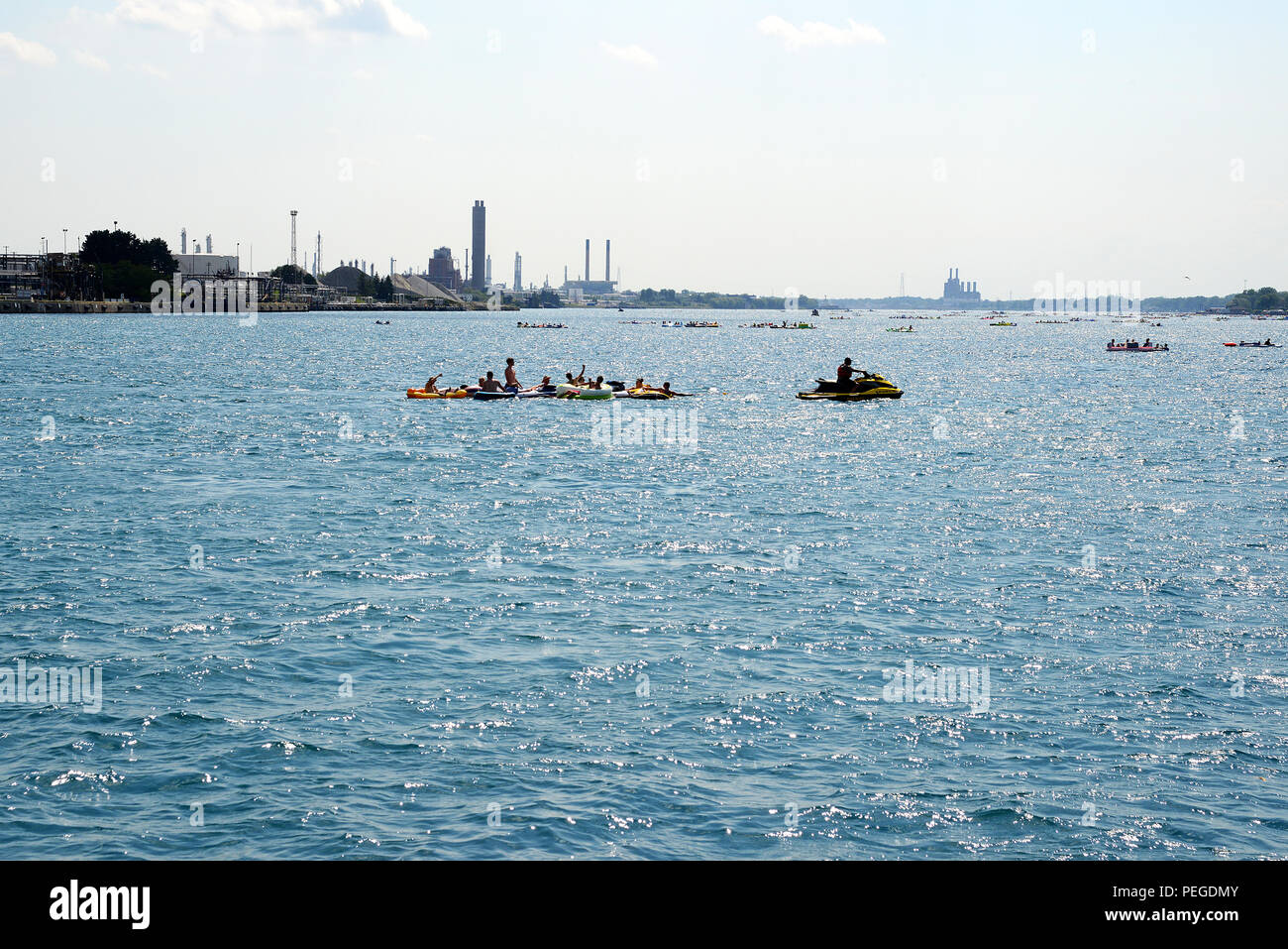 A law enforcement officer aboard a personal watercraft tows several people aboard inflatable rafts across the St. Clair River at the unsanctioned marine event known as the Port Huron Float Down, during which more than 1,000 people gathered Aug. 16, 2015, to float 7.5 miles down the St. Clair River between Port Huron, Mich. and Marysville, Mich., on the border of the U.S. and Canada in inflatable and makeshift rafts. Throughout the afternoon U.S. and Canadian emergency responders and law enforcement officers towed hundreds of people who were blown into Canadian waters and didn't have paddles to Stock Photo