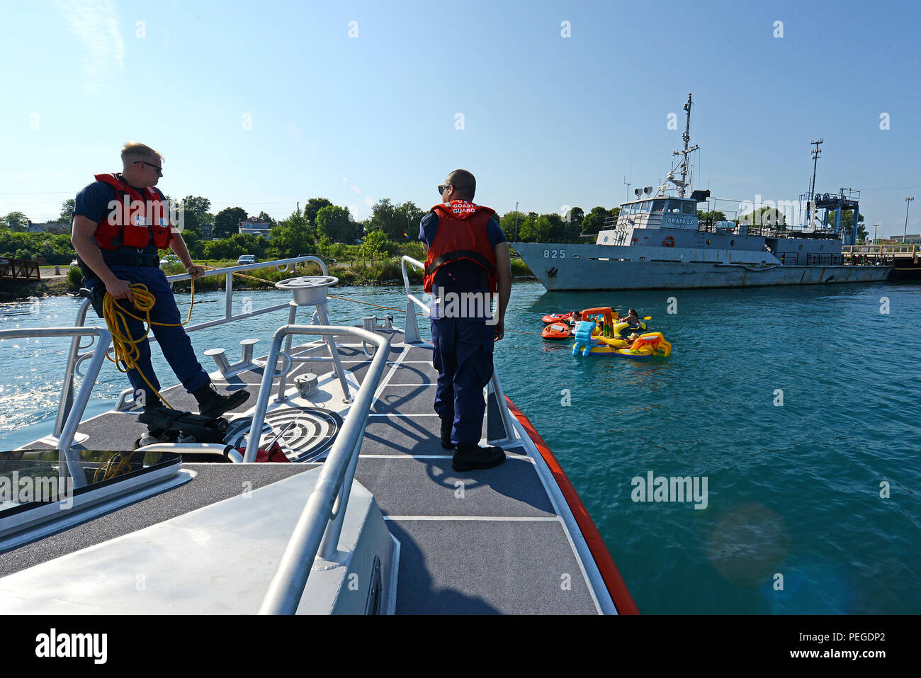 Petty Officer 3rd Class Steven Filgo and Petty Officer 1st Class Ingelheim Eribal of Coast Guard Station Port Huron, Mich., tow a group of people who were stuck in fast-moving current alongside a moored ship during the unsanctioned marine event known as the Port Huron Float Down, during which more than 1,000 people gathered Aug. 16, 2015, to float 7.5 miles down the St. Clair River between Port Huron and Marysville, Mich., on the border of the U.S. and Canada in inflatable and makeshift rafts. The event has no official organizer and poses significant and unusual hazards given the fast-moving c Stock Photo