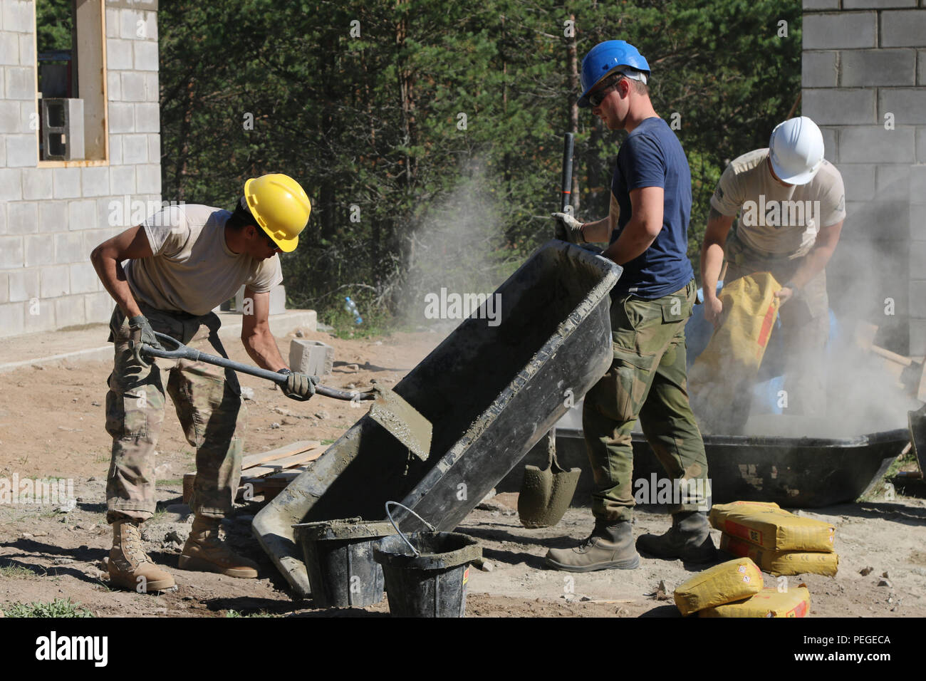 A Soldier of the Norwegian Army High Readiness Force tips a trough to assist a Soldier assigned to 500th Engineer Company, 15th Engineer Battalion, 18th Military Police Brigade, to ensure proper mixing of concrete during a wall construction project in the Central Training Area, Estonia, Aug. 18, as part of Operation Atlantic Resolve. Operation Atlantic Resolve is the United States' continued commitment to collective security through a series of actions designed to reassure NATO allies of America's dedication to enduring peace and stability in the region. (U.S. Army photo by Spc. Jacqueline Dow Stock Photo