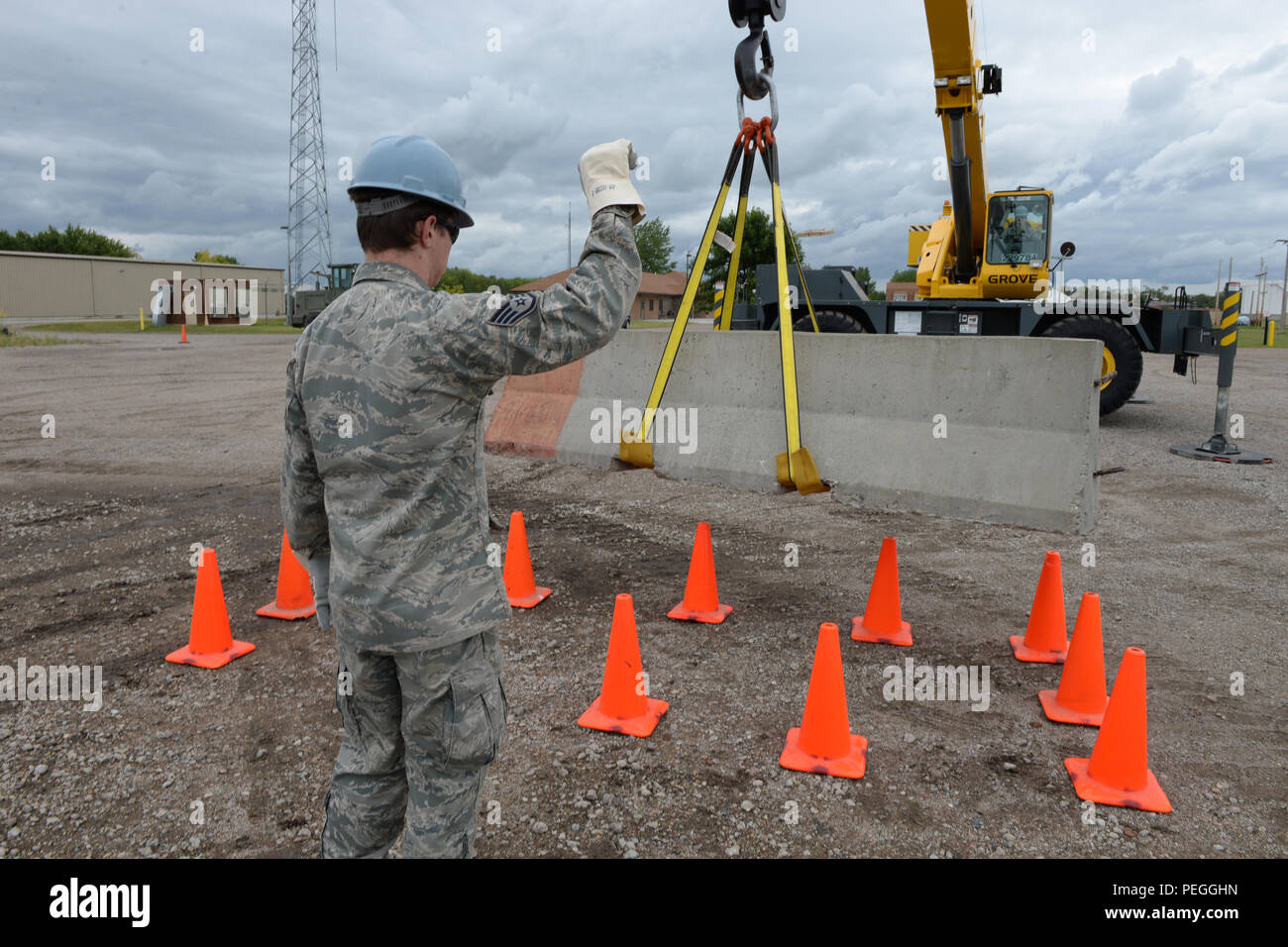 U.S. Air Force Staff Sgt. Austin Kemmer, of the 119th Civil Engineer Squadron, left, provides hand signals for Staff Sgt. Blake Robinson, of the 137th Civil Engineer Squadron, as he manipulates a concrete barrier into a target area using a crane as they train at the North Dakota Air National Guard Regional Training Site, Fargo, N.D., Aug. 19, 2015. The North Dakota Air National Guard Regional Training Site is one of five contingency training locations in the United States used by Air National Guard and U.S. Air Force personnel in the civil engineer career fields. I provides wartime mission tra Stock Photo