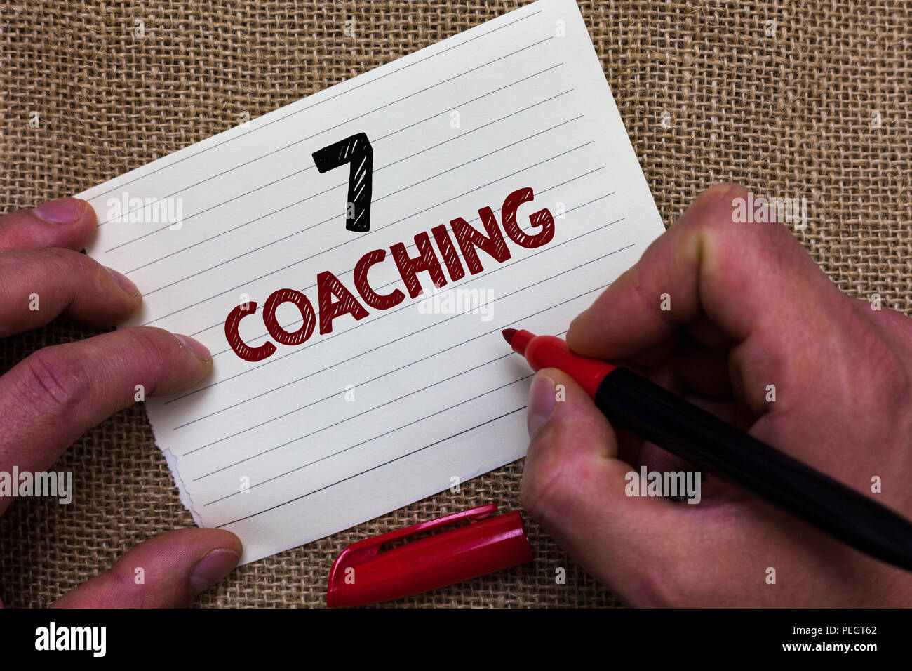 Writing note showing 7 Coaching. Business photo showcasing Refers to a number of figures regarding business to be succesful Man's hand hold white pape Stock Photo