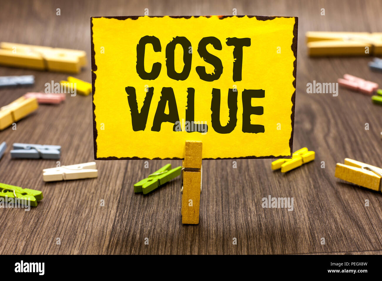Text sign showing Cost Value. Conceptual photo The amount that usualy paid for a item you buy or hiring a person Clothespin holding yellow paper note  Stock Photo