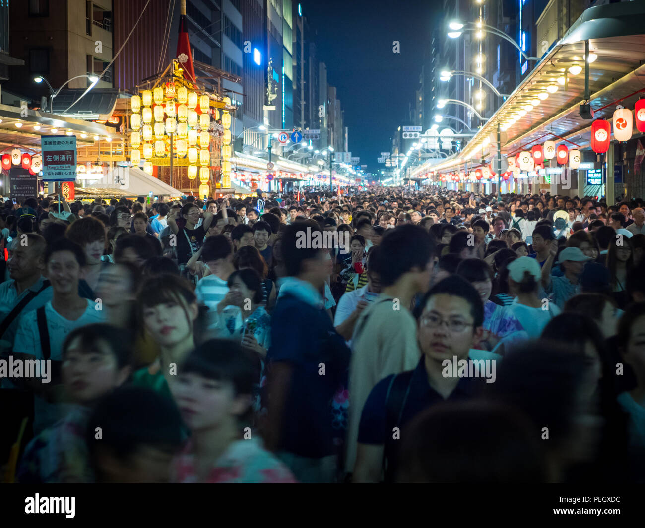 Crowds and the illuminated lanterns and floats of the Yoi-yoiyama (Yoiyama) street party during the Gion Matsuri Festival. Shijo-dori, Kyoto, Japan. Stock Photo