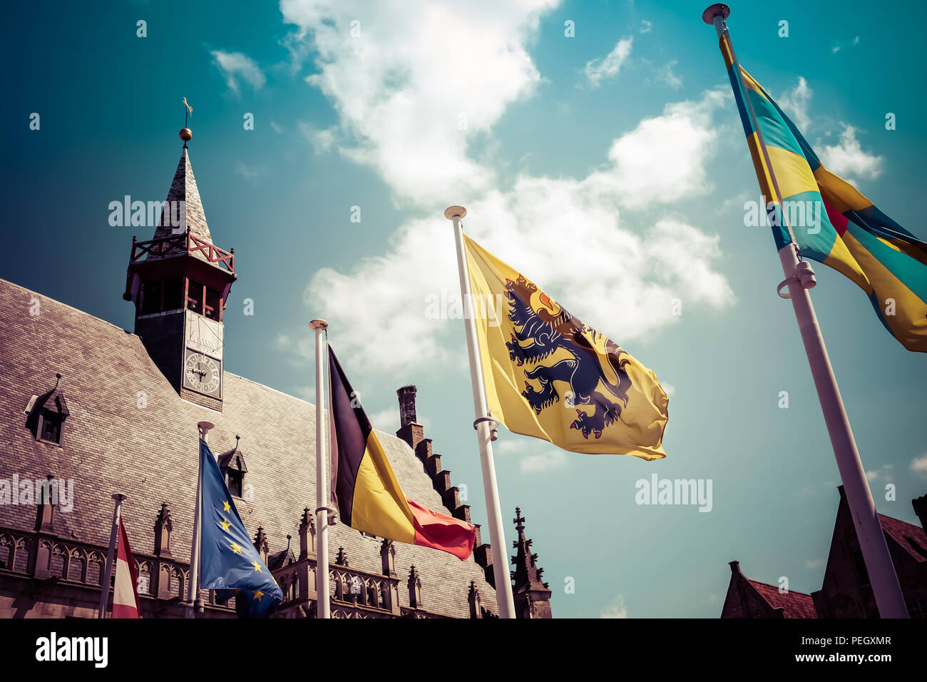 Landscape view of the city Hall of Damme in northern Belgium, with belgian, european and flemish flags in the foreground Stock Photo