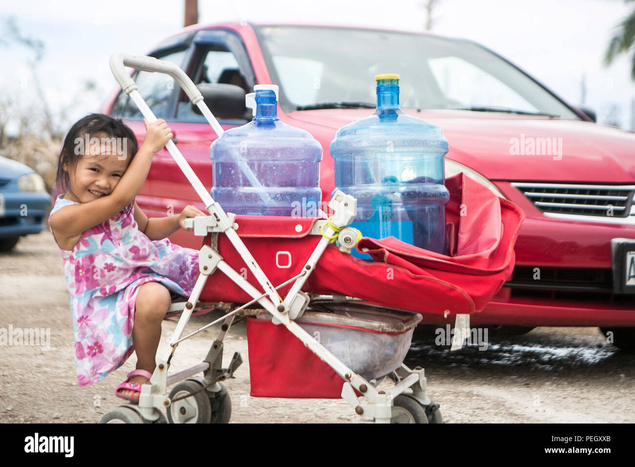 A young girl waits for her parents to fill water jugs while U.S. Marines with Combat Logistics Battalion 31, 31st Marine Expeditionary Unit, distribute water to local civilians during typhoon relief efforts in Saipan, Aug. 13, 2015. The Marines and sailors of the 31st MEU assisted the people of Saipan by producing and distributing potable water. The MEU was conducting training near the Mariana Islands when it was redirected to Saipan after the island was struck by Typhoon Soudelor Aug. 2-3. (U.S. Marine Corps photo by Lance Cpl. Brian Bekkala/Released) Stock Photo
