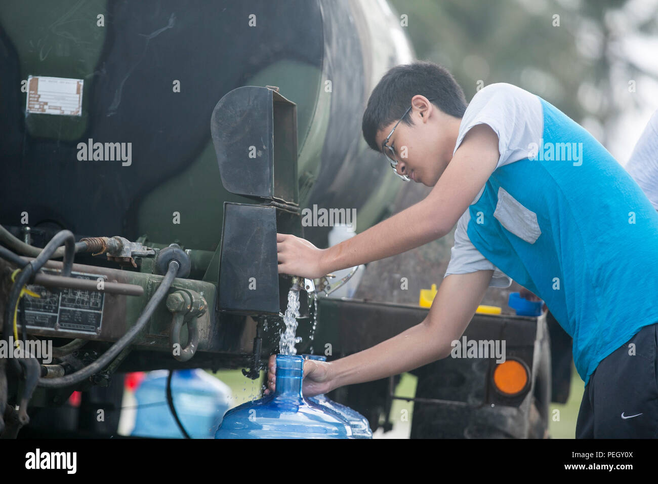 A young boy fills a water jug while U.S. Marines with Combat Logistics Battalion 31, 31st Marine Expeditionary Unit, distribute water to local civilians during typhoon relief efforts in Saipan, Aug. 13, 2015. The Marines and sailors of the 31st MEU assisted the people of Saipan by producing and distributing potable water. The MEU was conducting training near the Mariana Islands when it was redirected to Saipan after the island was struck by Typhoon Soudelor Aug. 2-3.  (U.S. Marine Corps photo by Lance Cpl. Brian Bekkala/Released) Stock Photo