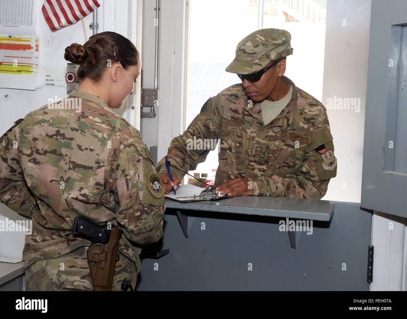 U.S. Air Force Staff Sgt. Brenda Hawkins, 455th Expeditionary Logistics Readiness Squadron non-commissioned officer in charge of the armory, gives paperwork to Senior Master Sgt. Vinetta Paige, 455 ELRS material management flight chief, prior is issuing her a weapon Aug. 26, 2015, at Bagram Air Field, Afghanistan. The armory team is responsible for issuing weapons to Airmen of the 455th AEW that do not deploy with but require a weapon during their deployment. (U.S. Air Force photo by Senior Airman Cierra Presentado/Released) Stock Photo