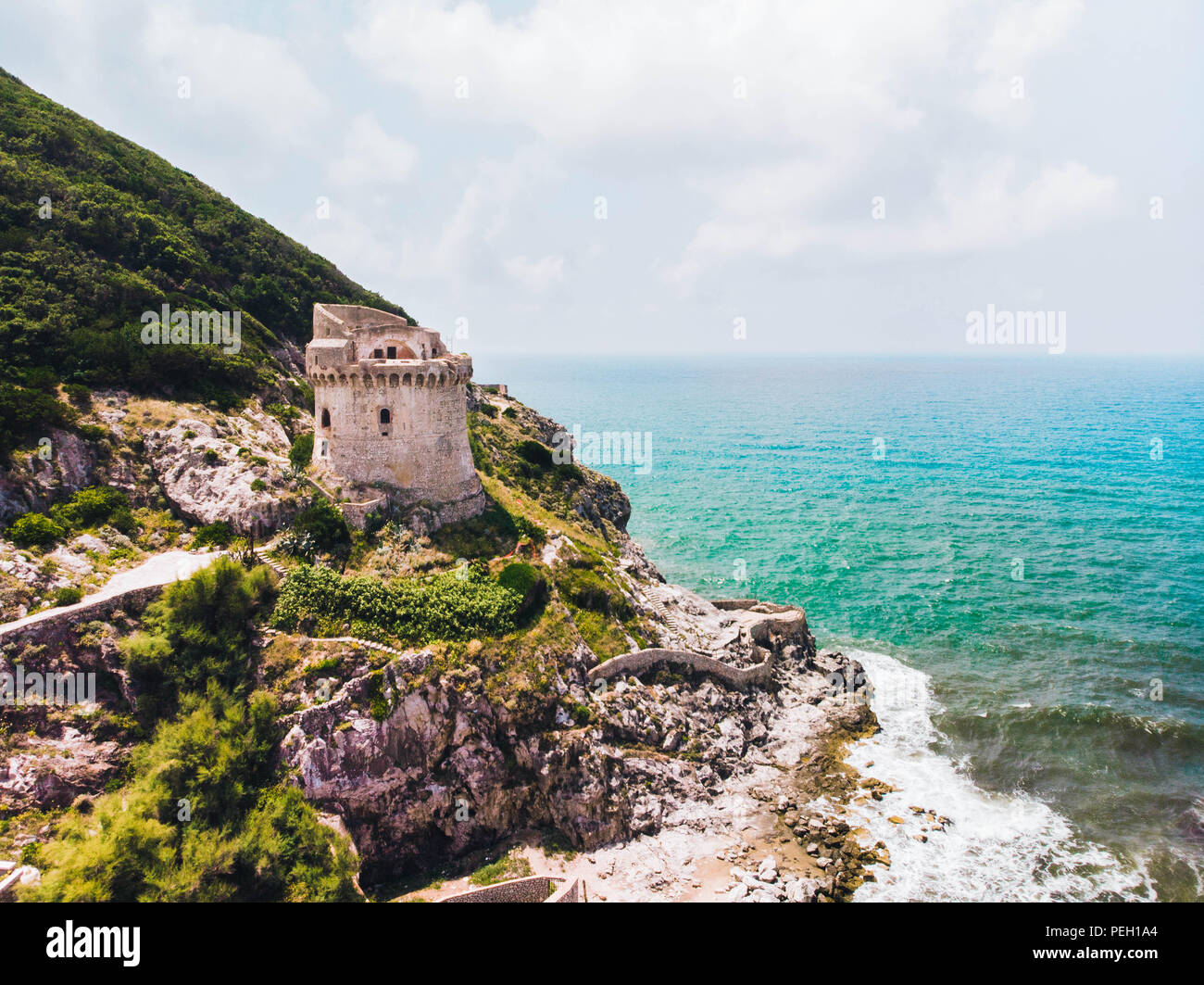 Beautiful scene, old building. Ancient defense tower on mountain in the Mediterranean sea. Paola tower is placed on Circeo promontory of Sabaudia, Italy. View from drone, aerial. Stock Photo