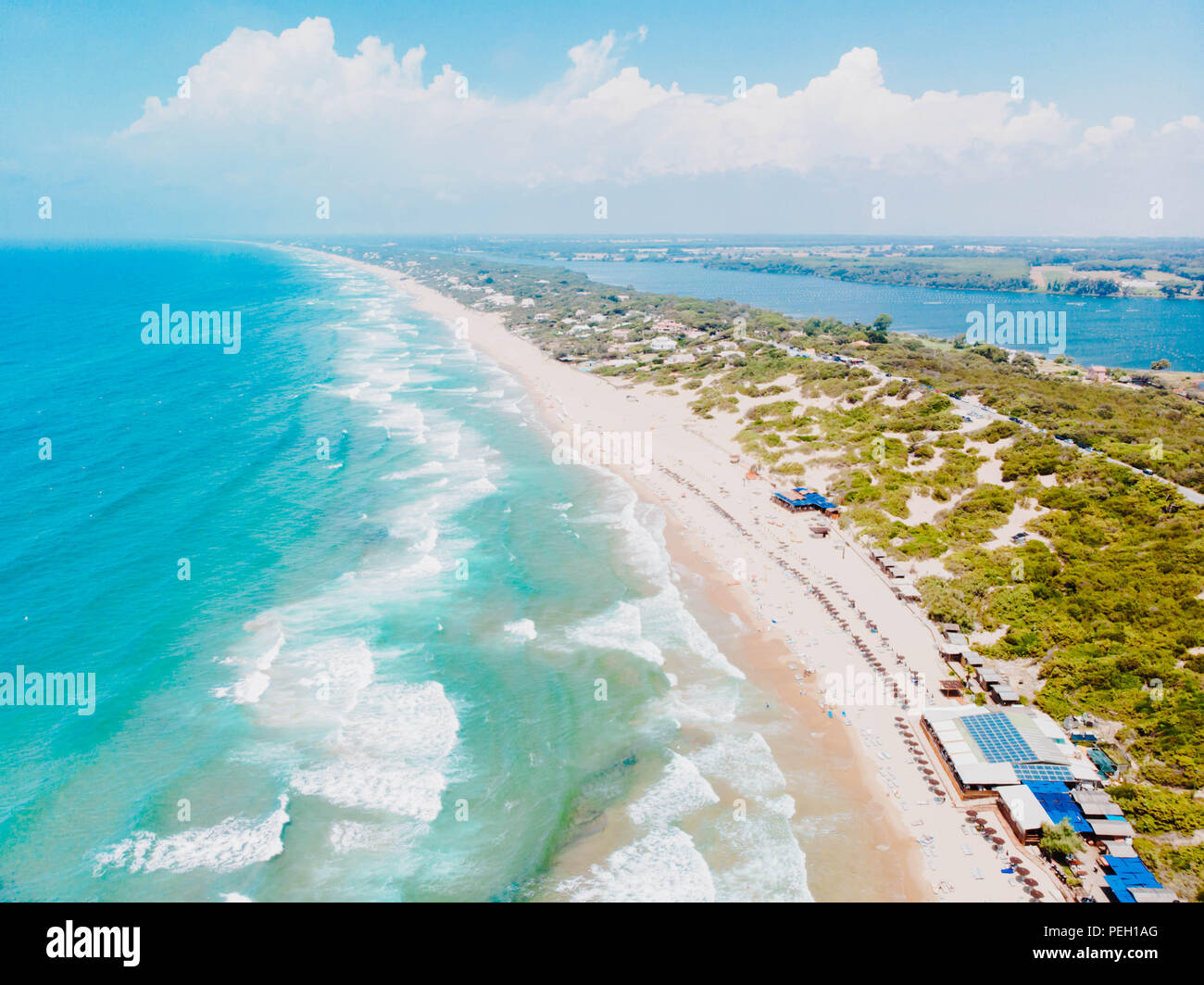 Aerial view from drone. People bathing in the sun, swiming and playing games on the beach. Tourists on the sand beach of Sabaudia, Italy. Lake on horizon Stock Photo