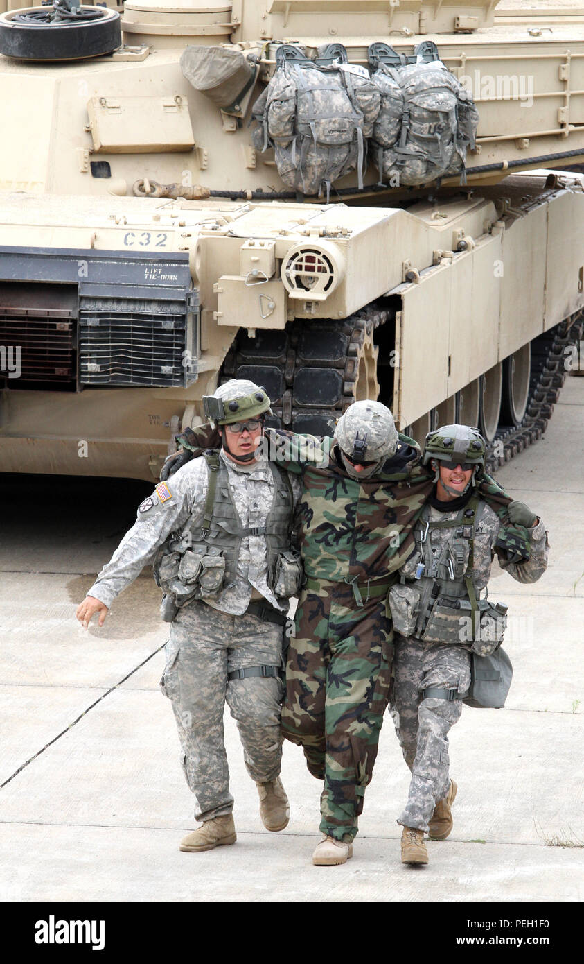 Two U.S. Army Reserve Soldiers rush a 'wounded' Soldier from the 1st Infantry Division, 16th Infantry Regiment, Fort Riley, Kan., to their M113 Armored Personnel Carrier while participating in the Combined Arms Breach during the Combat Support Training Exercise 86-15-03 on Fort McCoy, Wis., Aug. 23, 2015. The 84th Training Command’s third and final CSTX of the year hosted by the 86th Training Division at Fort McCoy, Wis., is a multi-component and joint endeavor aligned with other reserve component exercises including Diamond Saber, Red Dragon, Trans Warrior, and Exportable Combat Training Capa Stock Photo