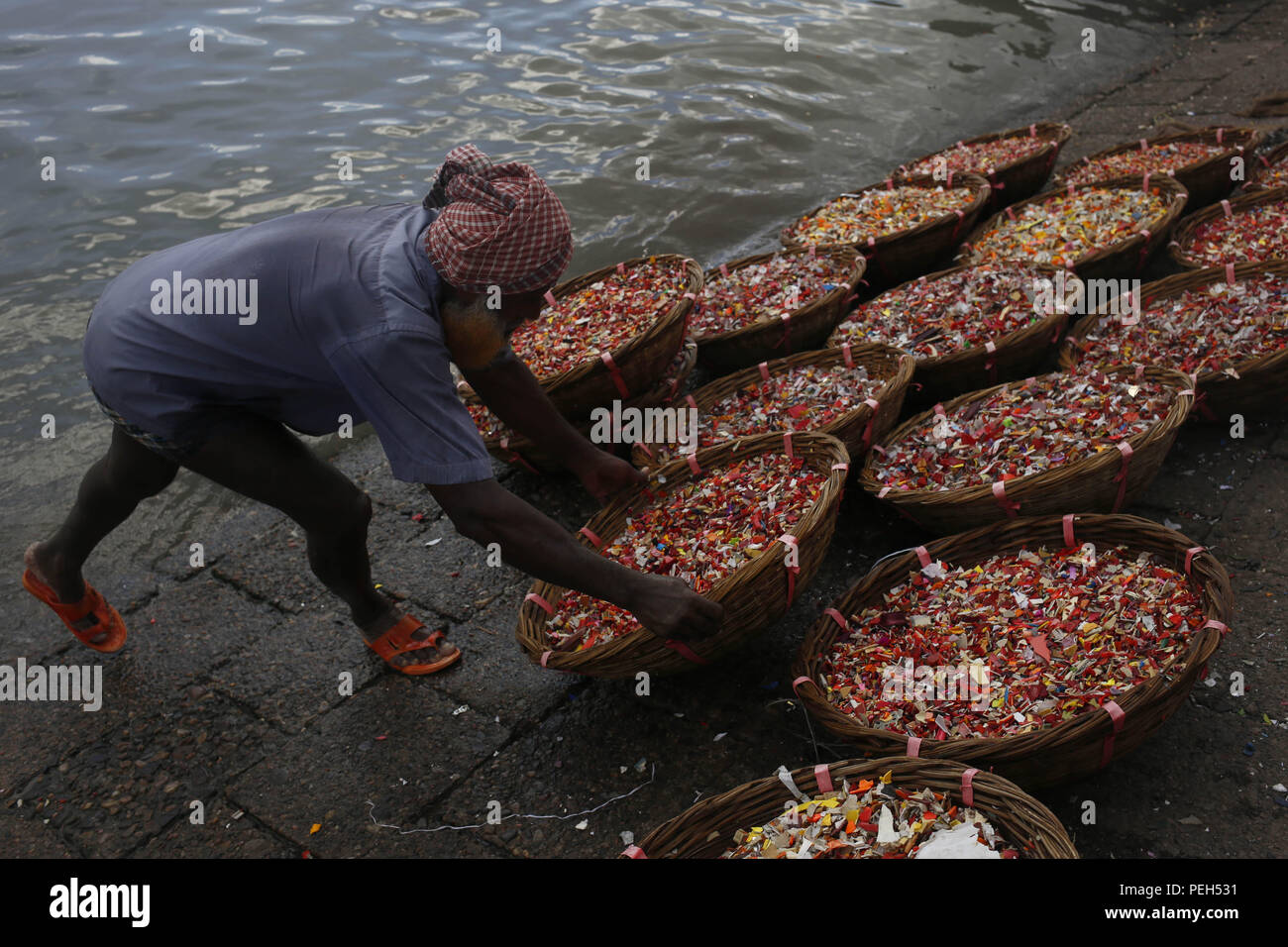 Dhaka, Bangladesh. 15th Aug, 2018. A labor arranges plastic grains after wash near Buriganga