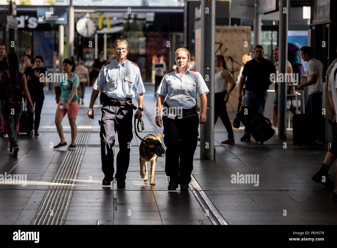 15 August 2018, Berlin, Germany: Sven Montwill (l) and Nancy Karras of DB Sicherheit run patrols with service dog Teufel at the inauguration of the second of a total of five new S-Bahn guards at Ostkreuz station. Security forces are there day and night, accompanied and supported by protection dogs. Photo: Christoph Soeder/dpa Stock Photo
