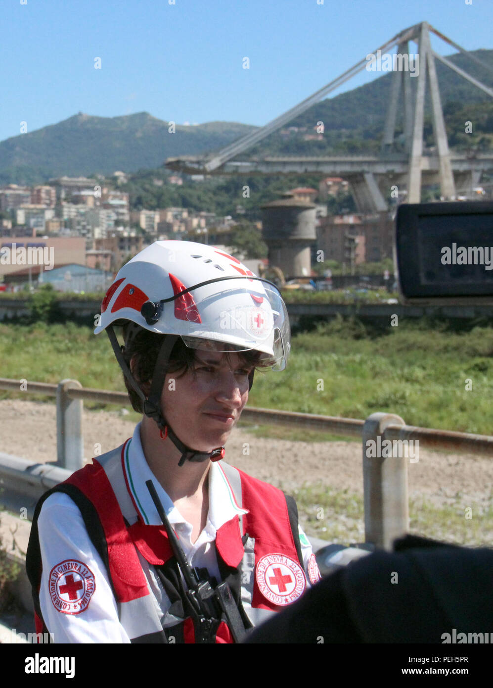 Genoa, Italy. 15th Aug, 2018. Federica Bornelli, of the Italian Red Cross, answers questions from journalists. One day after the collapse of the highway bridge Ponte Morandi (background), it is still being searched for survivors in the enormous ruins. Credit: Fabian Nitschmann/dpa/Alamy Live News Stock Photo