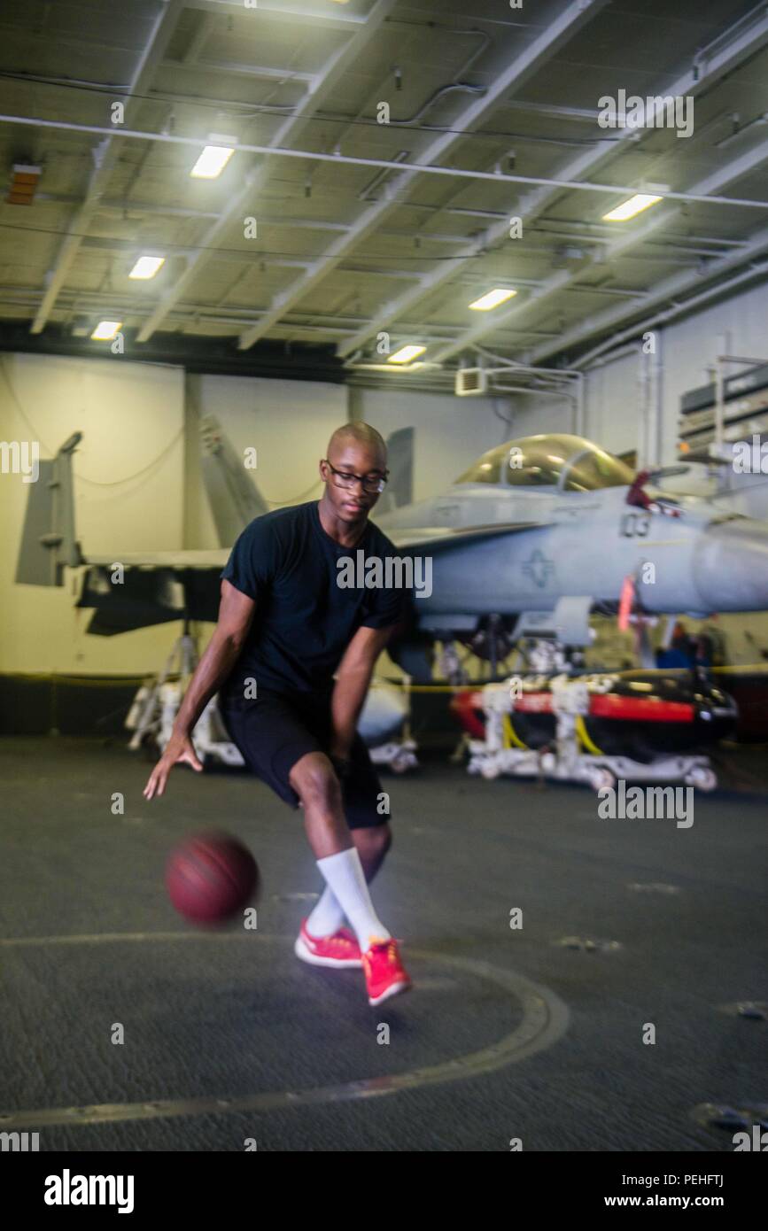 150821-N-DA737-195 PACIFIC OCEAN (Aug. 21, 2015) - Aviation Ordnanceman 3rd Class Damone Hardy, from Detroit, dribbles a basketball in a hangar bay aboard USS John C. Stennis (CVN 74). Sailors from the John C. Stennis Strike Group are undergoing Composite Training Unit Exercise and Joint Task Force Exercise (COMPTUEX/JTFEX), the final step in certifying to deploy. (U.S. Navy photo by Mass Communication Specialist 3rd Class Jonathan Jiang / Released) Stock Photo