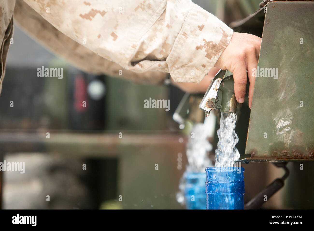 A U.S. Marine with Combat Logistics Battalion 31, 31st Marine Expeditionary Unit, fills water jugs for civilians during typhoon relief efforts in Saipan, Aug. 14, 2015.  The Marines with Echo Company, Battalion Landing Team 2nd Battalion, 5th Marines, 31st MEU and CLB 31, 31st MEU, assisted the locals of Saipan by producing and distributing potable water. The Marines and sailors of the 31st MEU were conducting training near the Mariana Islands when they were redirected to Saipan after the island was struck by Typhoon Soudelor Aug. 2-3. (U.S. Marine Corps photo by Lance Cpl. Brian Bekkala/Relea Stock Photo