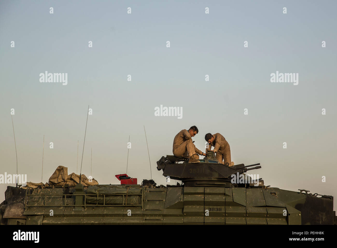 KUWAIT (Aug. 18, 2015) U.S. Marine Lance Cpl. Anthony Gomez (left) and Cpl. Christopher Jimerson perform routine maintenance on an Amphibious Assault Vehicle (AAV-7) before a live-fire and maneuver exercise. Gomez and Jimerson are both crewmen with Kilo Company, Battalion Landing Team 3rd Battalion, 1st Marine Regiment, 15th Marine Expeditionary Unit (MEU). During the training, Marines engaged targets with the Browning .50 caliber machine gun at unknown distances from AAV-7. Elements of the 15th MEU are ashore in Kuwait for sustainment training to maintain and enhance the skills they developed Stock Photo