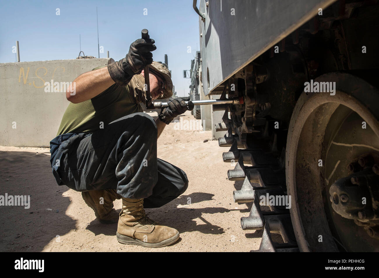 KUWAIT (Aug. 22, 2015) U.S. Marine Lance Cpl. John Figueroa checks the suspension on an Amphibious Assault Vehicle (AAV-7). Figueroa is a crewman with Kilo Company, Battalion Landing Team 3rd Battalion, 1st Marine Regiment, 15th Marine Expeditionary Unit (MEU). These Marines maintain the AAVs to ensure they remain in good condition and are operable in extreme environments. Elements of the 15th MEU are ashore in Kuwait for sustainment training to maintain and enhance the skills they developed during their pre-deployment training period.  The 15th MEU is embarked on the Essex Amphibious Ready Gr Stock Photo