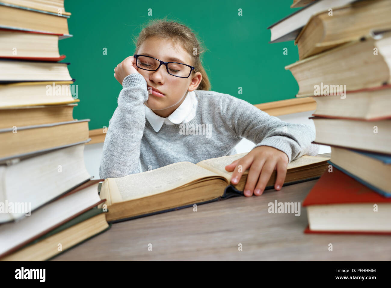 Schoolgirl fell asleep among the books. Photo of little girl in classroom. Education concept Stock Photo