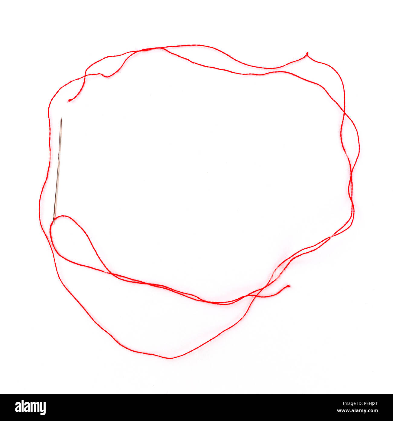 Overhead photo of a needle with a red thread, forming a frame for ...