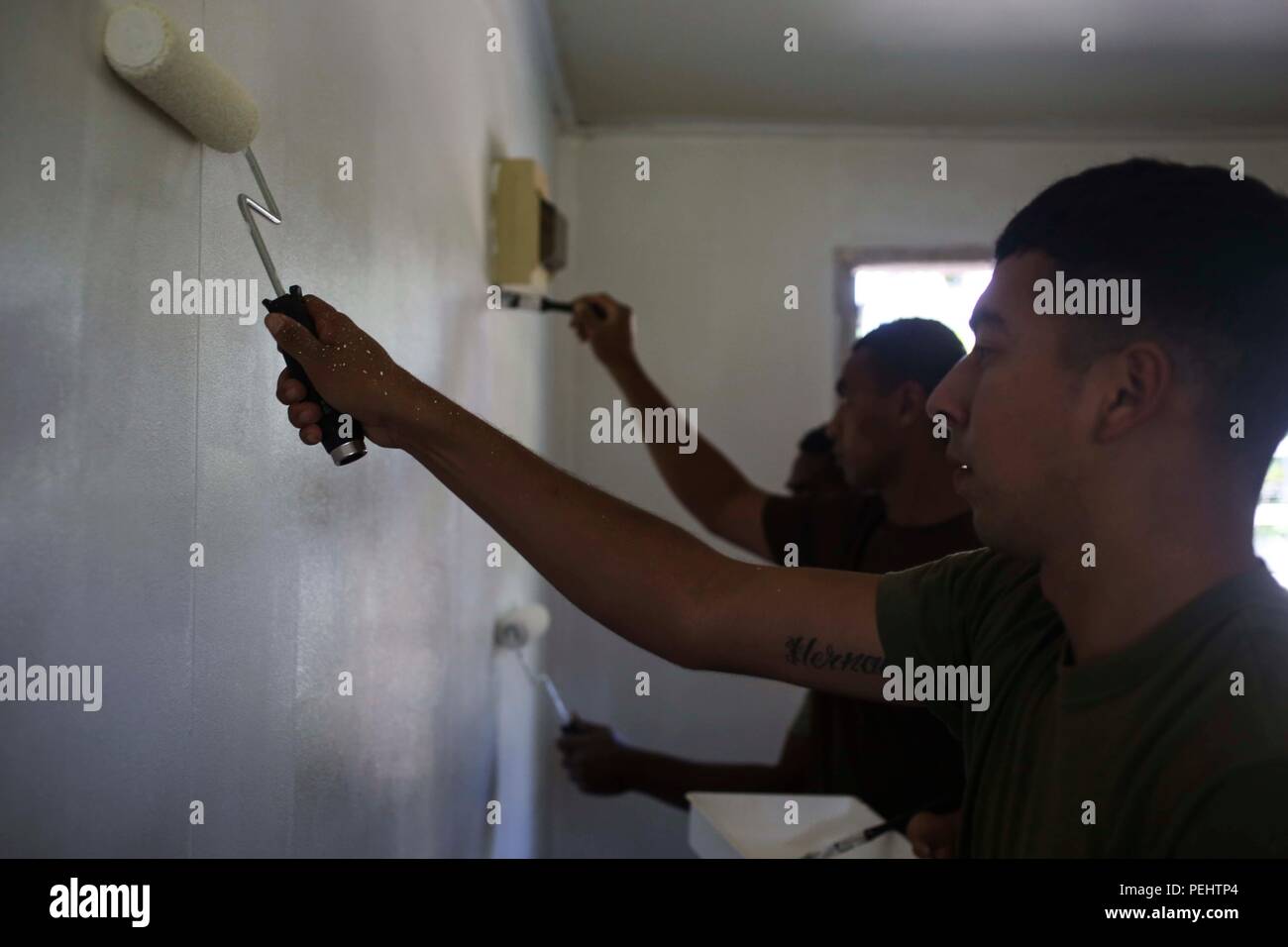 U.S. Marines with Company B, 1st Battalion, 4th Marine Regiment, Marine Rotational Force – Darwin, paint the interior walls of a classroom with troops from His Majesty’s Armed Forces, the New Zealand Defence Force, the French Army of New Caledonia and the Tongan Royal Guards Aug. 28 at a local school on Tongatapu Island, Tonga. The multilateral group accomplished community services with the school during Exercise Tafakula 15. U.S. Marines are good neighbors who are engaged with and contribute to host communities. They are immersed in the local culture, engaged with their hosts, and contribute  Stock Photo