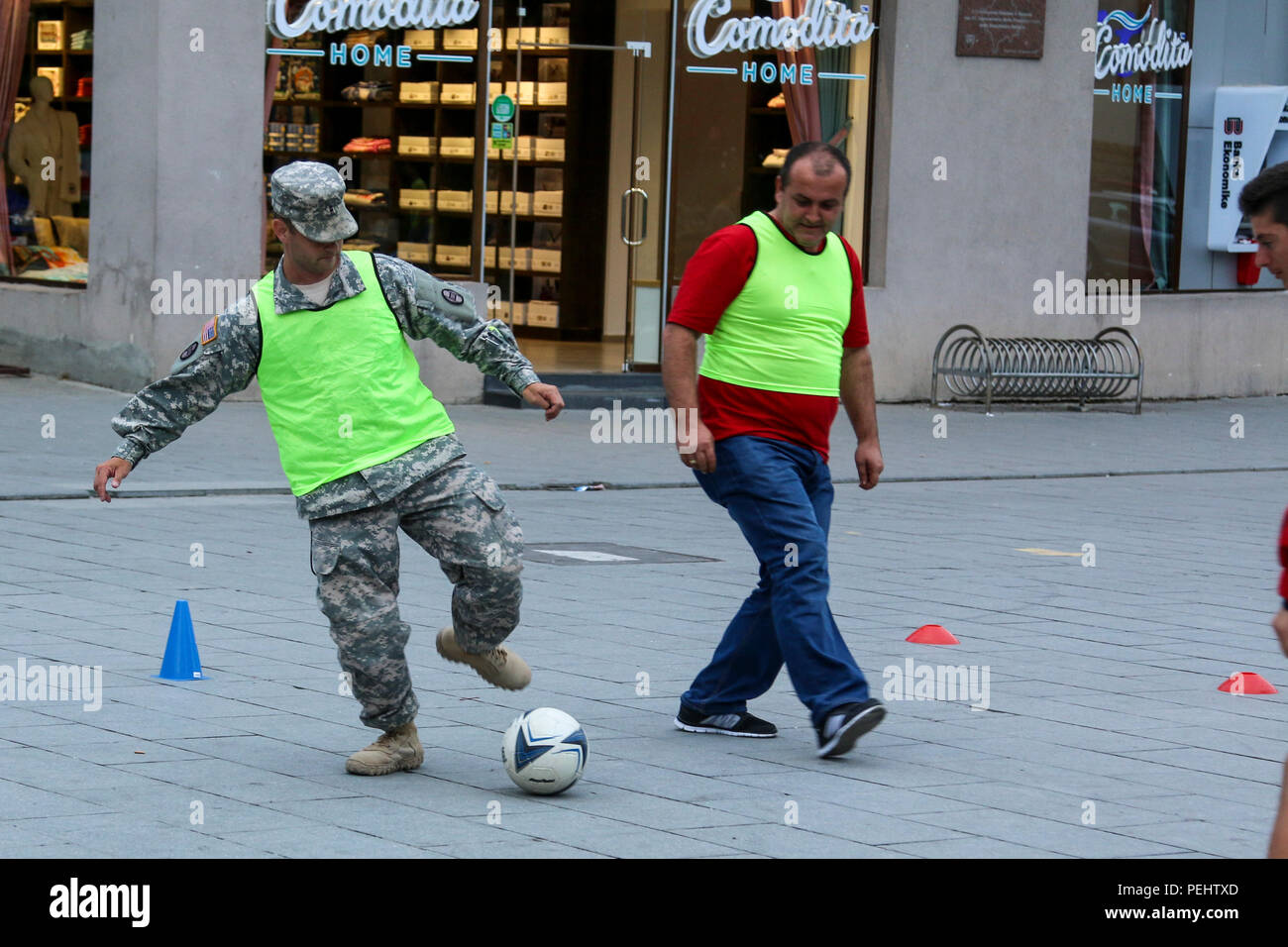 Chief Warrant Officer 2 Jason Boyd, a North Carolina National Guard Soldier deployed to Kosovo with the 30th Armored Brigade Combat Team headquarters, kicks a soccer ball while leading a game about stereotypes and prejudice, Aug. 22, 2015, at the Anibar International Animation Festival in Peja, Kosovo. Boyd and other U.S. Army Soldiers serving in Kosovo volunteered their off-time to support the Pristina Rotary Club’s Violence-Free Future program, which uses games to mimic real-life situations, then discusses them in hopes of promoting pro-social behavior among Kosovo’s youth. The 30th ABCT hea Stock Photo