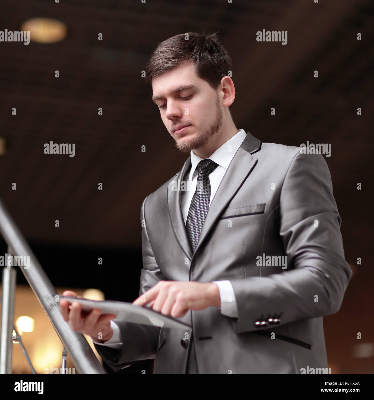 Handsome businessman standing on steps using tablet in office building Stock Photo