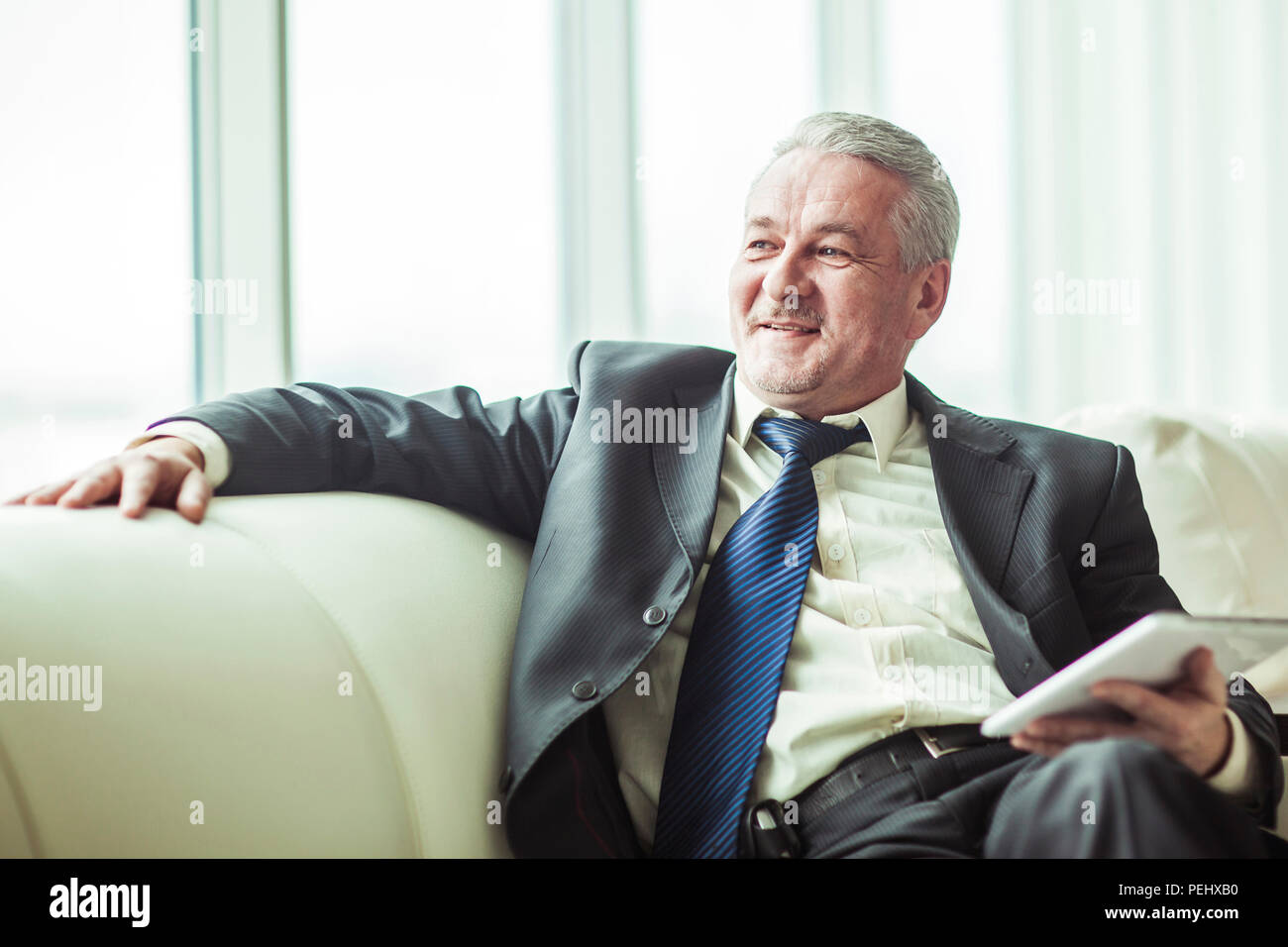 experienced lawyer with digital tablet sitting on the sofa in the private office Stock Photo