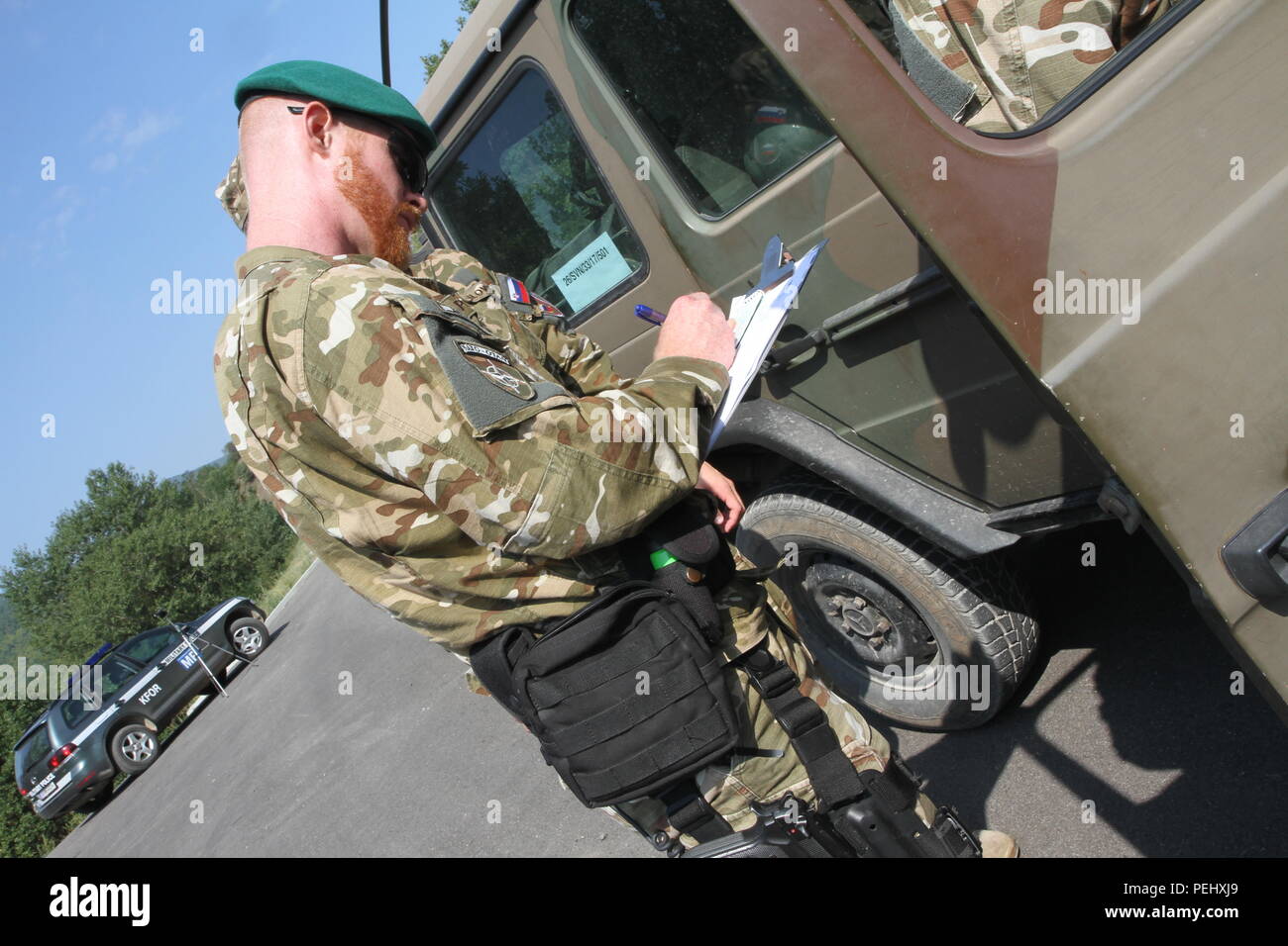 Slovenian 1st Lt. Blaz Primc, the commander for Slovenian military police in Kosovo, performs a joint traffic control point inspection with Kosovo Force International Military Police to ensure soldiers are carrying proper credentials and following safety procedures while driving, Aug. 26, 2015, outside Camp Nothing Hill near Leposavic, Kosovo. The TCPs are set up as a safety measure for multinational forces under NATO to make sure they are operating within the proper regulations in support of freedom of movement and a safe and secure environment in Kosovo. (U.S. Army photo by Sgt. Erick Yates, Stock Photo