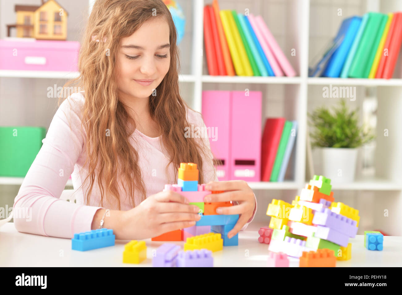 Curly teen girl playing with colorful plastic blocks Stock Photo - Alamy