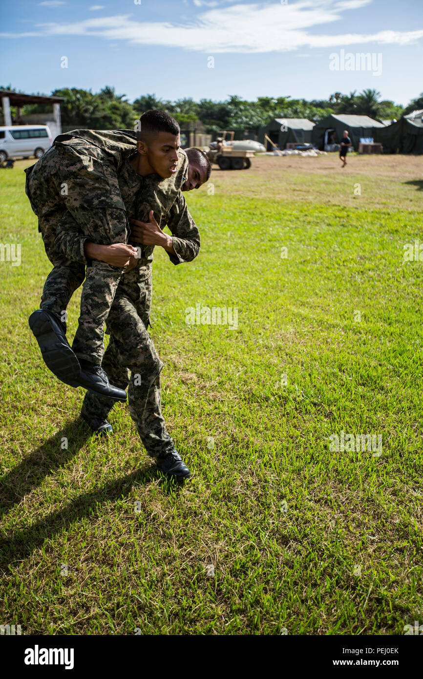 A Honduran fireman carries another marine during the maneuver under fire portion of the combat fitness test at Naval Base Puerto Castilla, Honduras, Aug. 12, 2015. U.S. Marines with Security Cooperation Team-Honduras, Special Purpose Marine Air-Ground Task Force-Southern Command monitored the event. SCT-Honduras is currently deployed as part of the SPMAGTF-SC to assist the Centro de Adiestramiento Naval with implementing a training curriculum to create a Honduran marine Program.  (U.S. Marine Corps Photo by Cpl. Katelyn Hunter/Released). Stock Photo