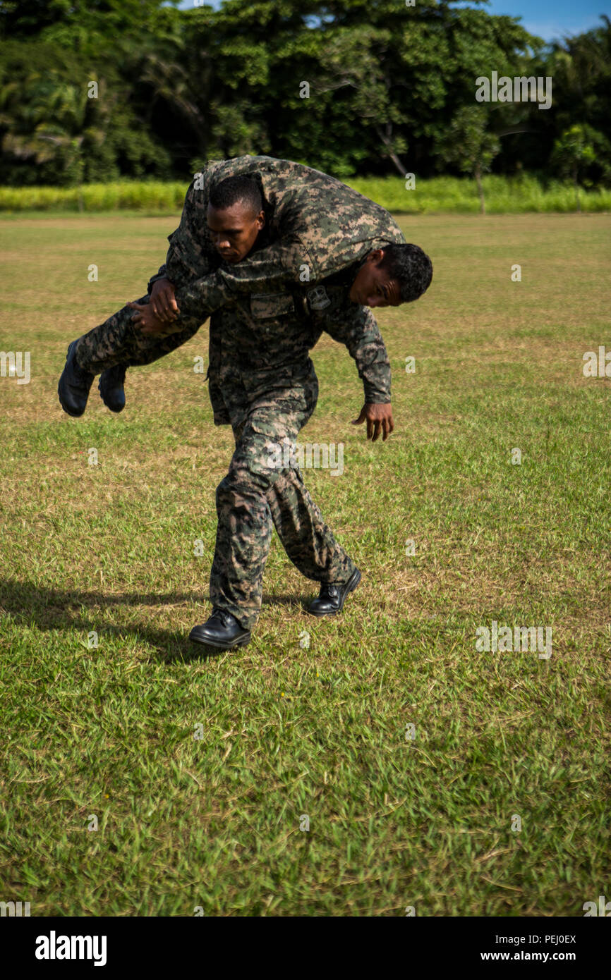 A Honduran marine fireman carries another marine during the maneuver under fire portion of the combat fitness test at Naval Base Puerto Castilla, Honduras, Aug. 12, 2015. U.S. Marines with Security Cooperation Team-Honduras, Special Purpose Marine Air-Ground Task Force-Southern Command monitored the event. SCT-Honduras is currently deployed as part of the SPMAGTF-SC to assist the Centro de Adiestramiento Naval with implementing a training curriculum to create a Honduran marine Program.  (U.S. Marine Corps Photo by Cpl. Katelyn Hunter/Released). Stock Photo