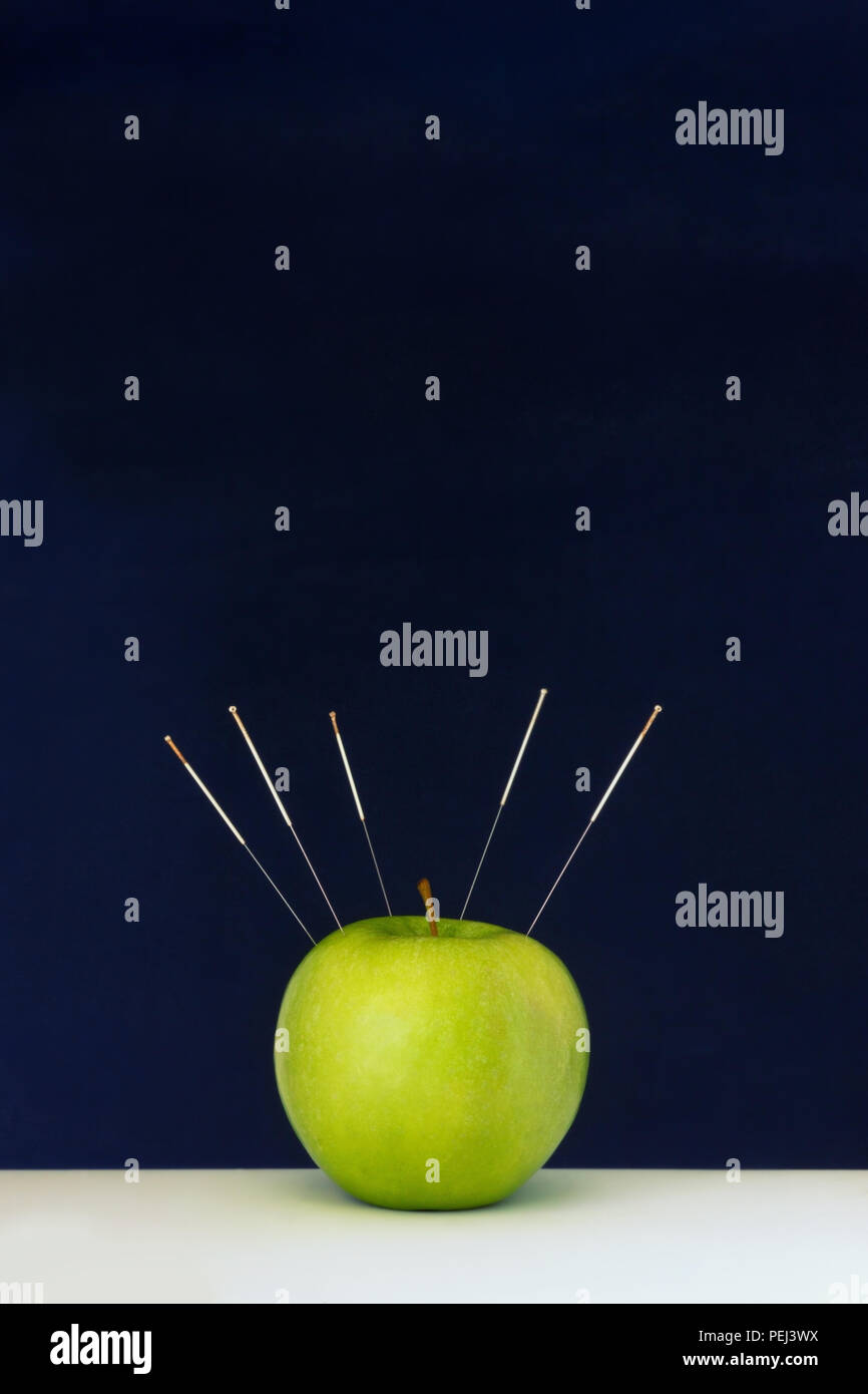 Acupuncture needles stuck into a green apple as a symbol of precision treatment Stock Photo Alamy