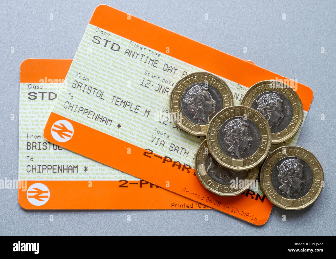 Two uk British rail railway train tickets with pound coins on top of ...