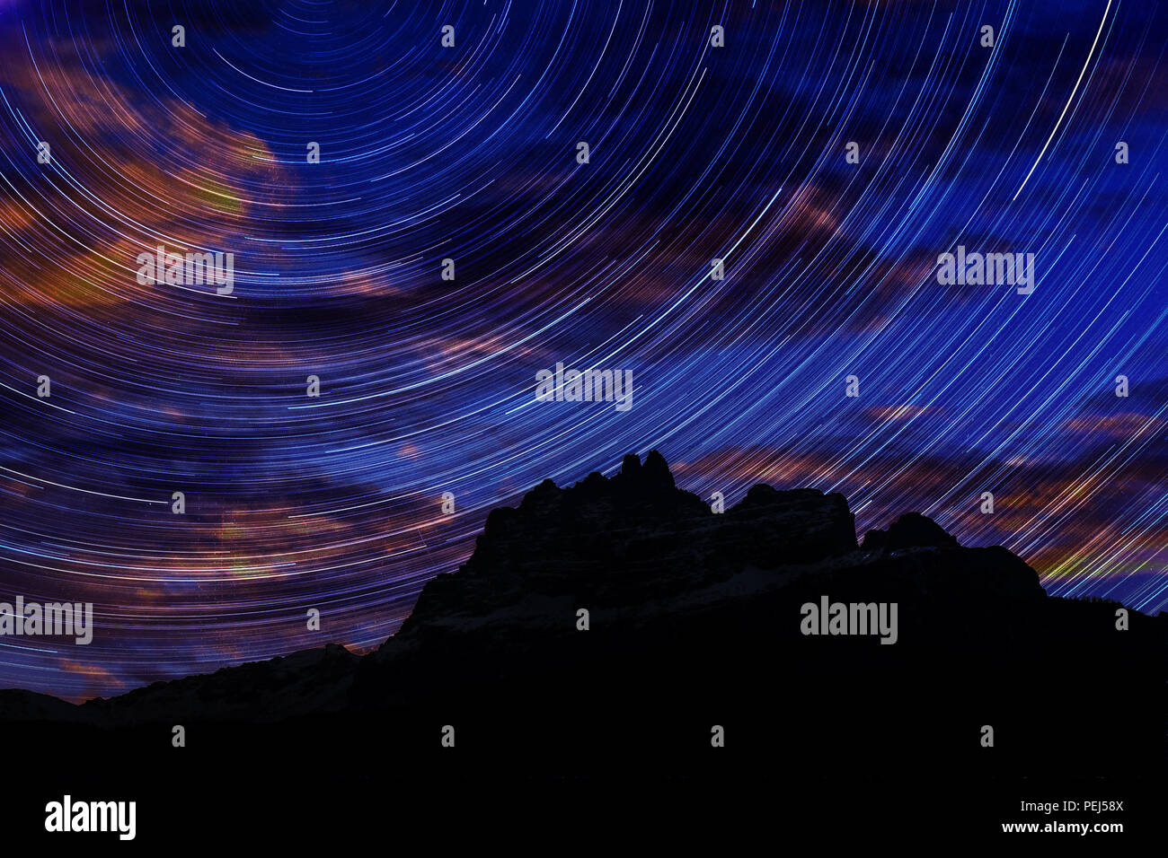 Long exposure image showing Night sky star trails over mountains Stock Photo