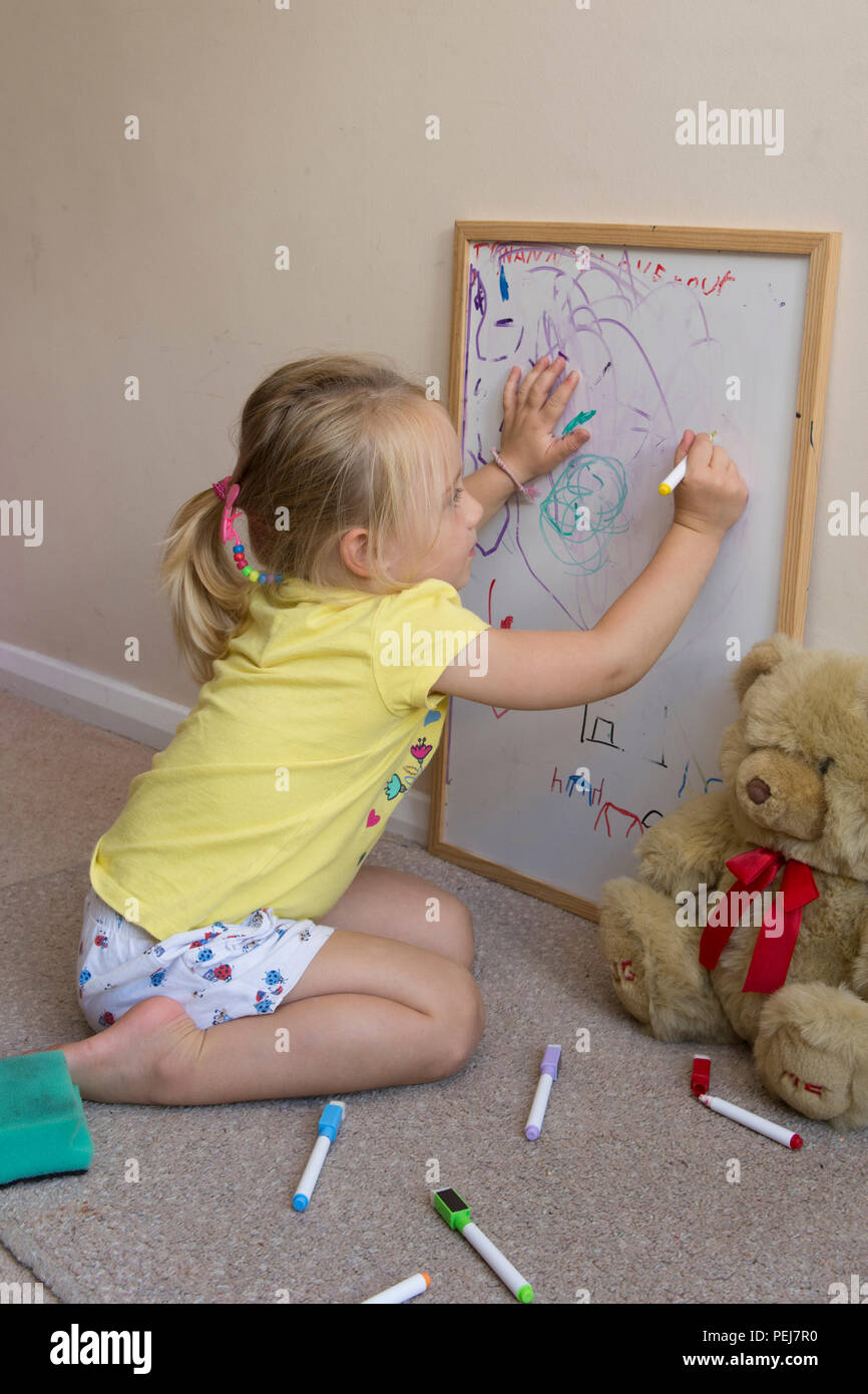 young two year old girl drawing with coloured pen on white board, being artistic, Stock Photo