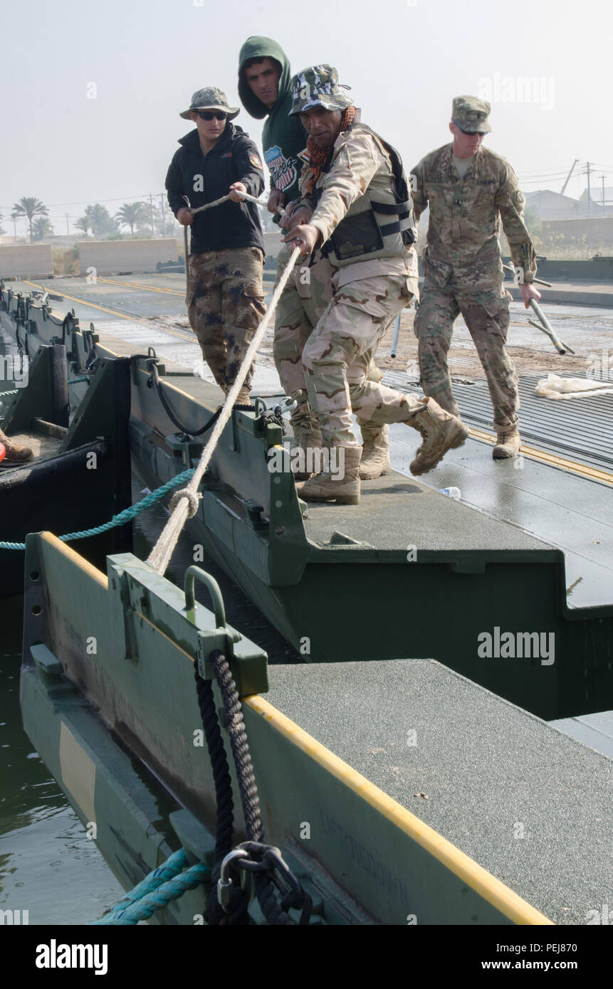 Iraqi engineers with the 15th Iraqi Army Division, pull an interior bay toward an improved ribbon bridge (IRB) that is being assembled as part of Building Partner Capacity training in Baghdad, Nov. 20, 2015. The IRB training is being facilitated by the U.S. Army Soldiers with the 814th Multi-Role Bridging Company out of Fort Polk, La. This training will provide the Iraqi soldiers with freedom of maneuver and additional options for conducting operations. With the proper equipment and training, the IA will no longer be restricted to roads and will be able to cross any size river during operation Stock Photo