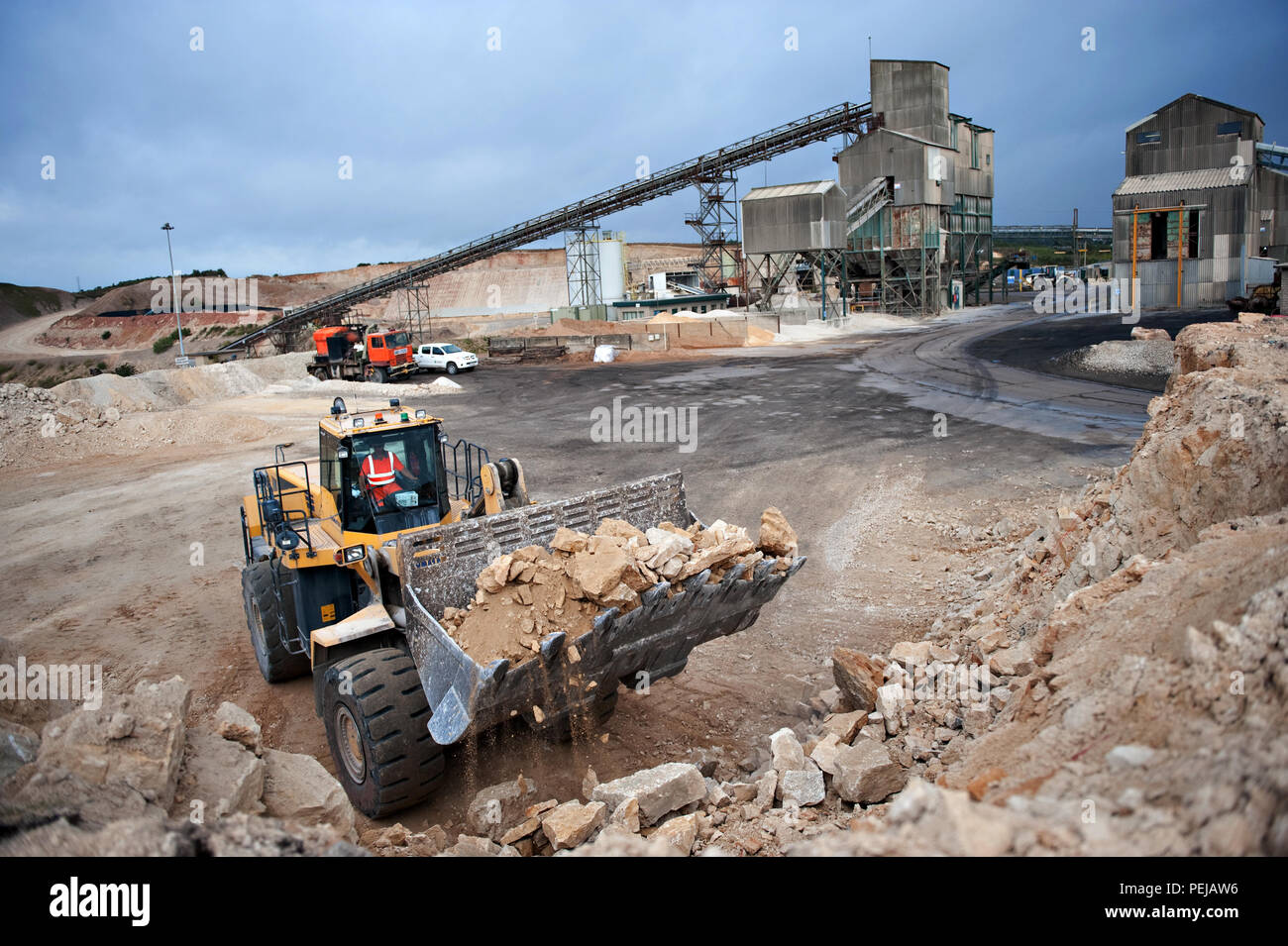 Excavating and picking up mined aggregate from the quarry floor, in a