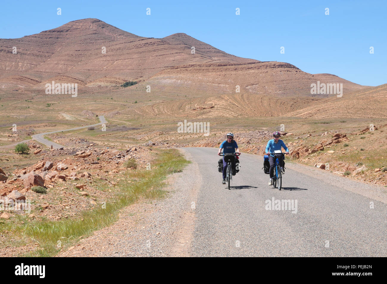 Two cyclists make their way through the dramatic geology of the Anti Atlas mountains Stock Photo
