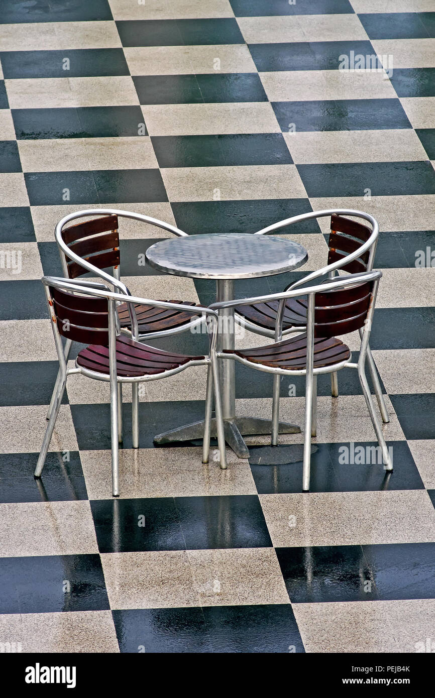 A Vacant Chrome Table And Four Chairs Sit Unused On A Checkerboard