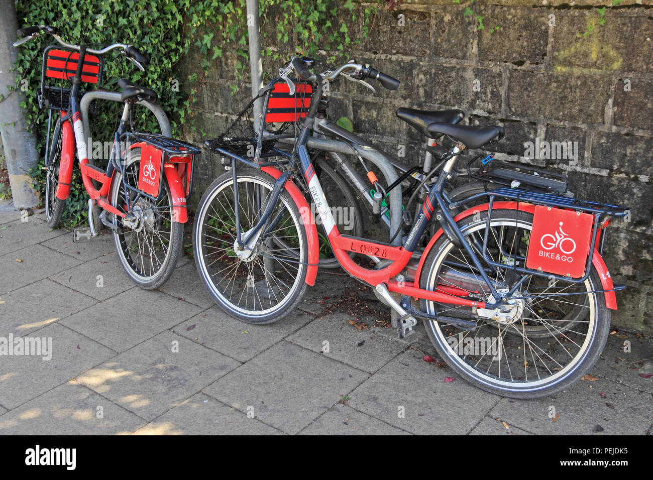 Red, Bike & Go Rental bikes locked at side of road. Stock Photo