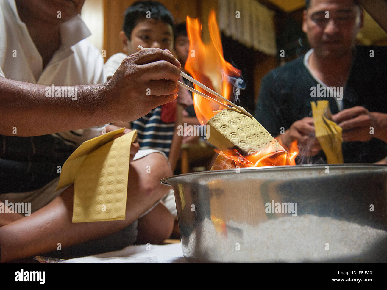 Sousei Yamakawa, owner of the house, burns uchikabi, money of the other world, during the last day of Obon in Yomitan village, Okinawa, Japan, Aug. 28, 2015. During Obon, a lot of businesses are closed and many people travel to be with their relatives. (U.S. Air Force photo by Naoto Anazawa) Stock Photo
