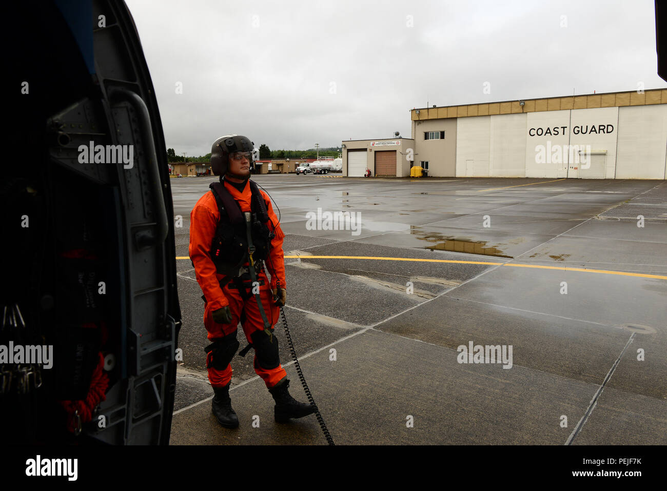 Petty Officer 2nd Class James Rizer, an aviation electronics technician and qualified flight mechanic, prepares to conduct final aircraft checks prior to take off from Coast Guard Air Station Astoria, Ore., Aug. 28, 2015. This flight was headed to the San Juan Islands in the Puget Sound to assist with an aids-to-navigation mission. (U.S. Coast Guard photo by Petty Officer 1st Class Levi Read) Stock Photo