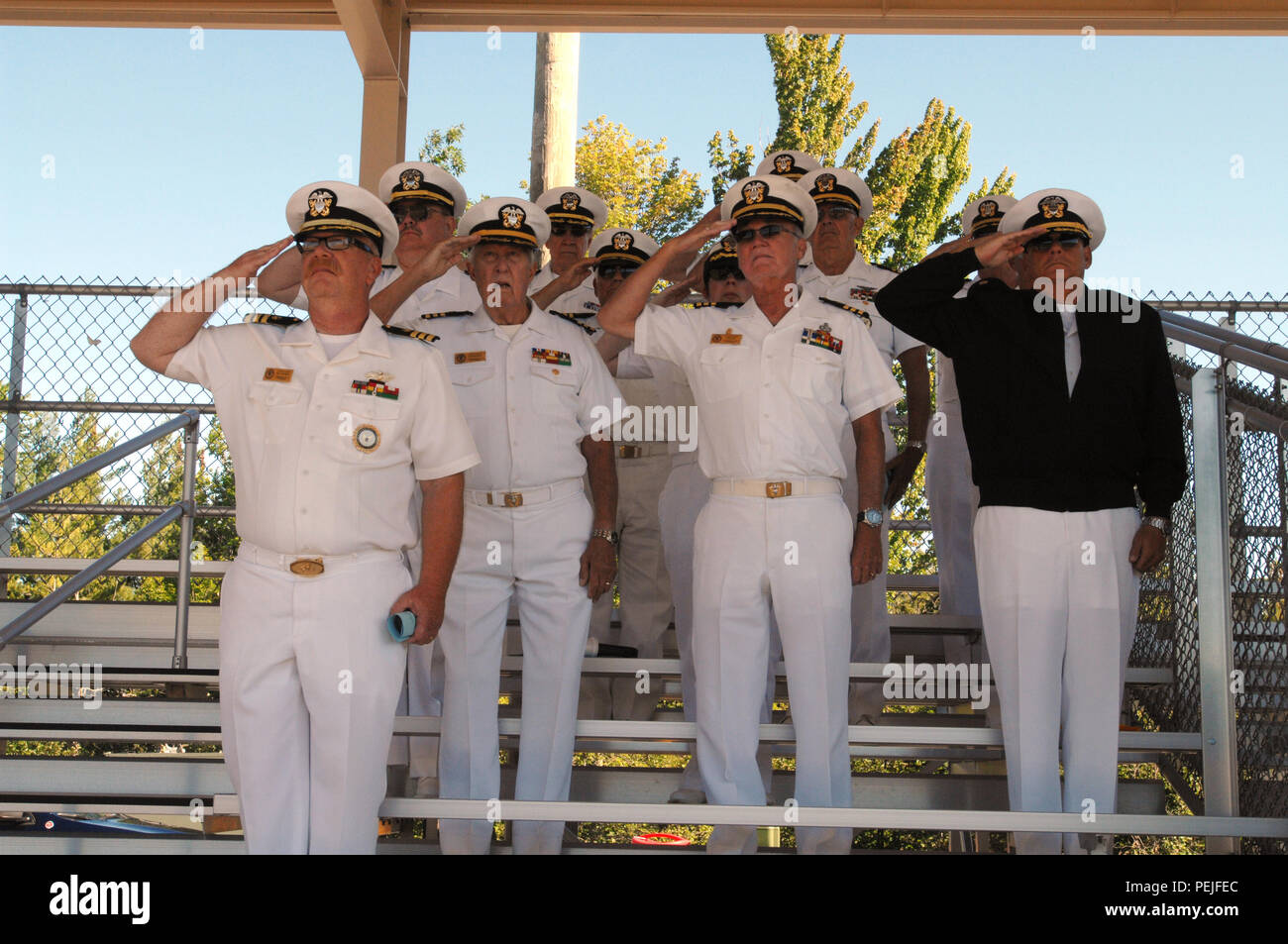 Members of the Naval Commander's Club of Michigan salute during the national anthem at the start of the Michigan Army National Guard pass in review of troops and memorial ceremony at Camp Grayling Joint Maneuver Training Center, Grayling, Mich., Aug. 21, 2015. The club is comprised of former military from all branches of the military. (U.S. Air National Guard photo by Master Sgt. Denice Rankin/Released) Stock Photo