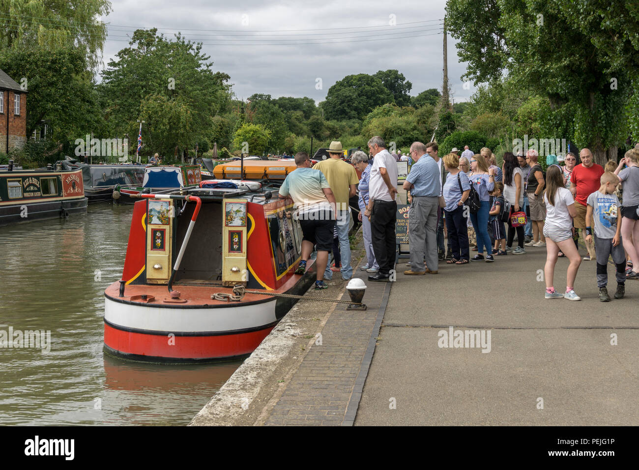 Queue of visitors waiting to board the narrowboat 'Charlie' for a trip on the canal, Stoke Bruerne, Northamptonshire, UK Stock Photo